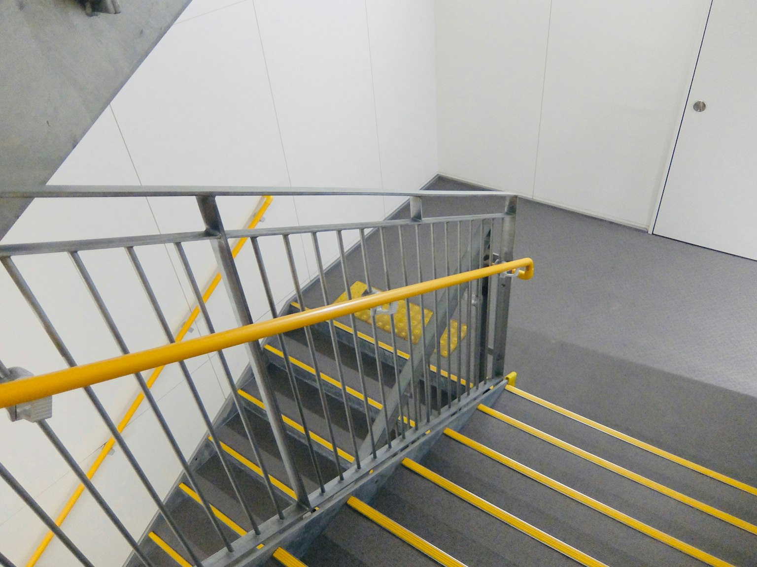 Escalier intérieur avec une marche rayée jaune et une rampe