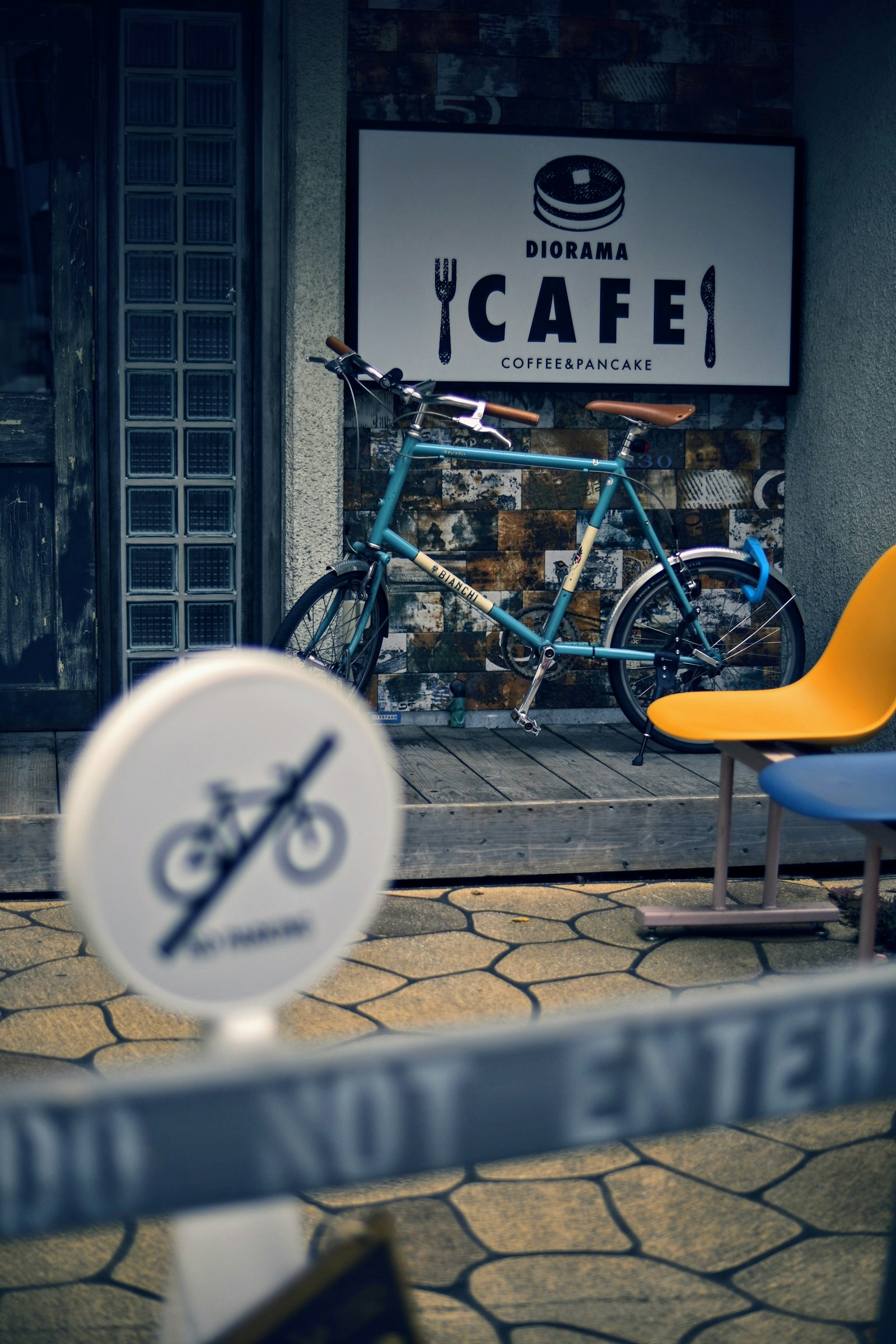 Un vélo bleu à côté d'un panneau de café avec une chaise moderne