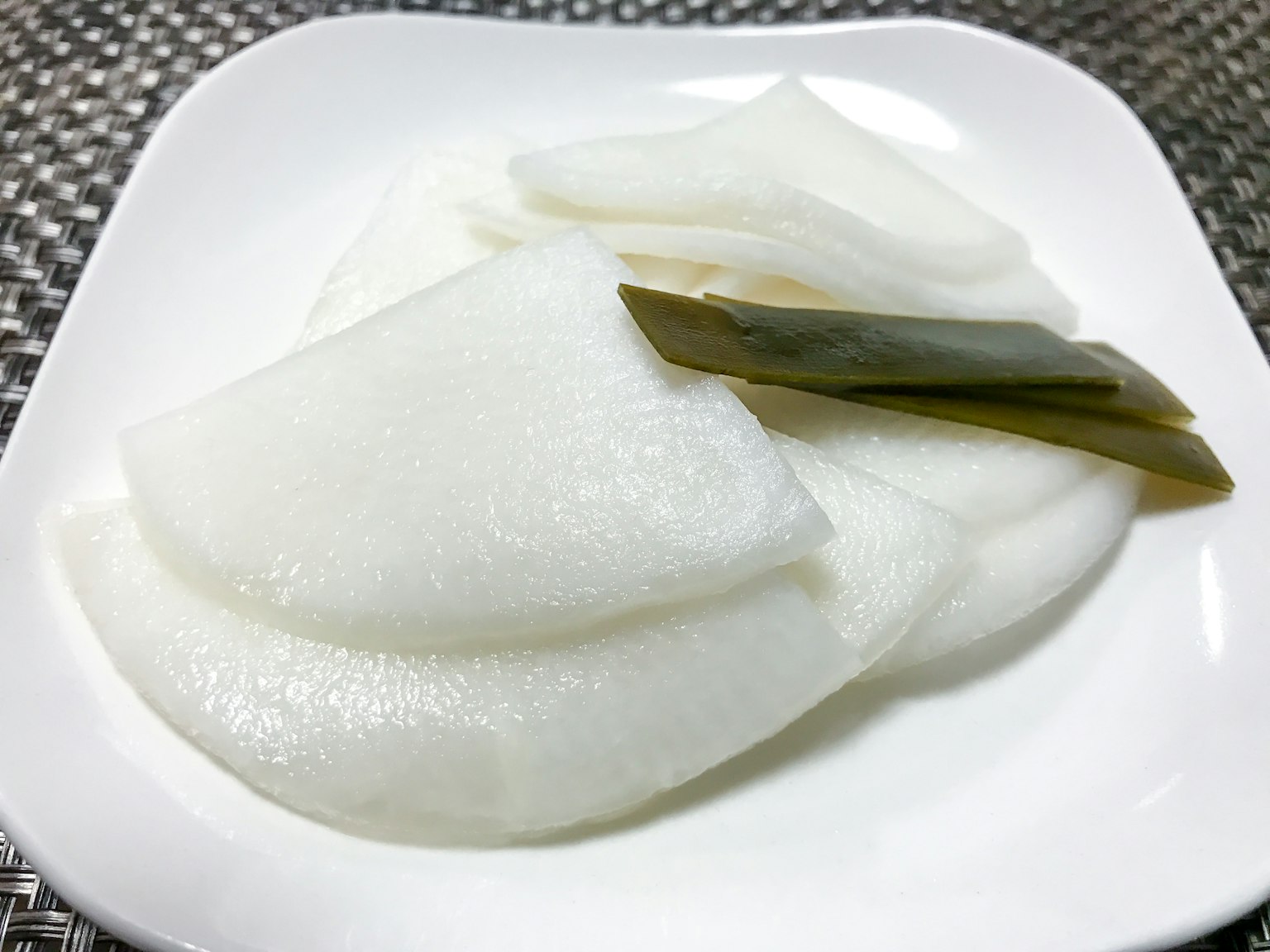 薄切的白蘿蔔醃菜放在白色盤子裡