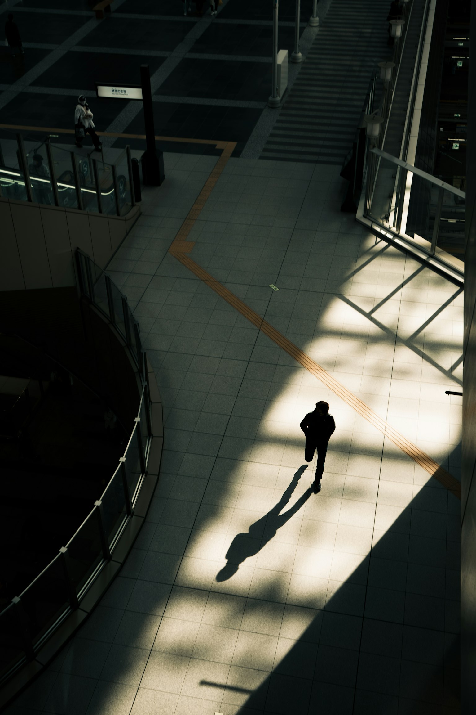 Silhouette di una persona che cammina su un marciapiede in ombra