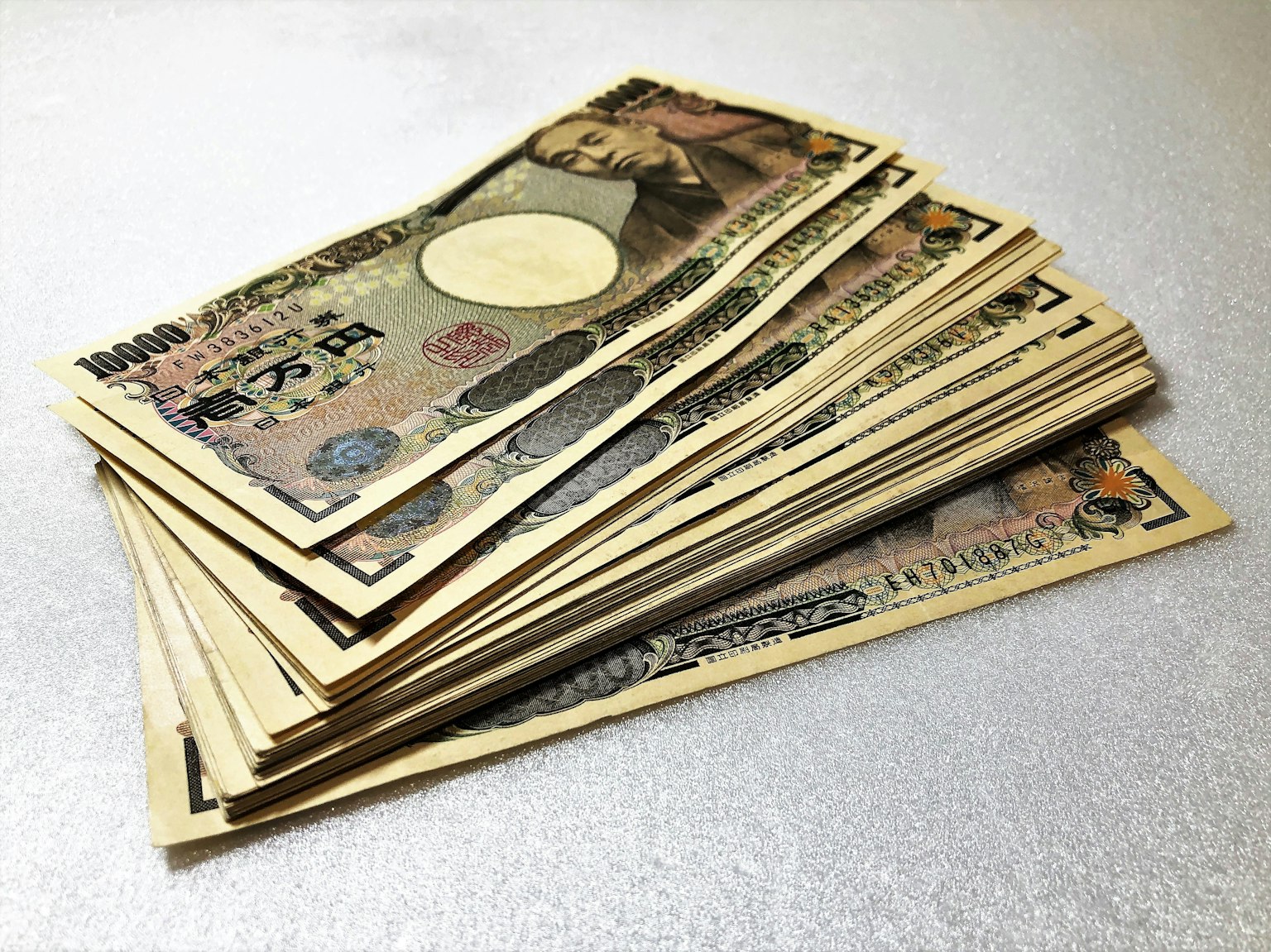 Mucchio di banconote in yen giapponesi su uno sfondo argentato