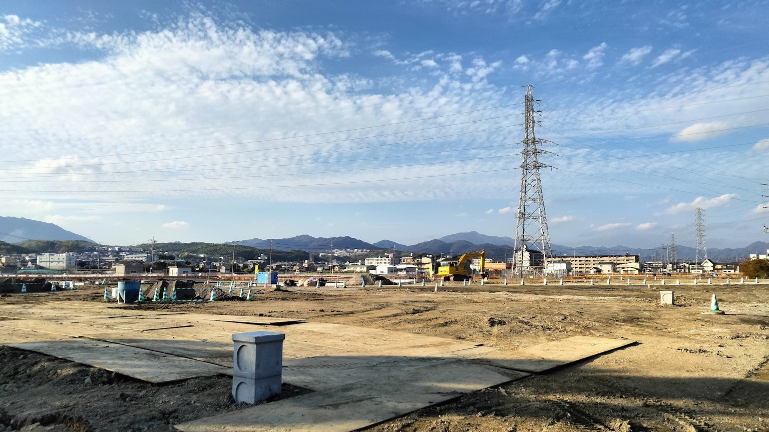 Vista de un cielo amplio y un sitio de construcción con líneas eléctricas al fondo