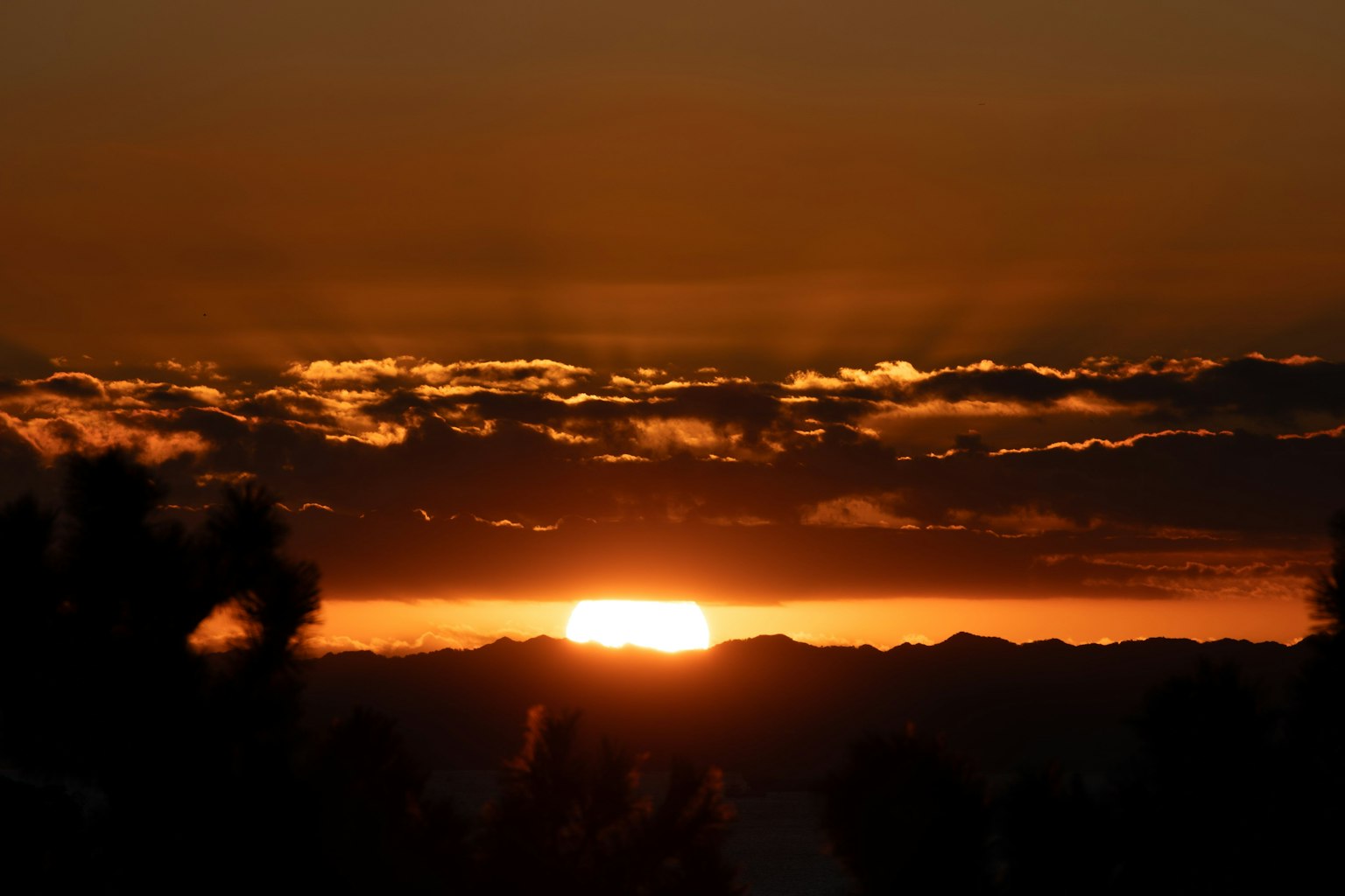 Bellissimo paesaggio del tramonto dietro le montagne con cielo arancione profondo e nuvole