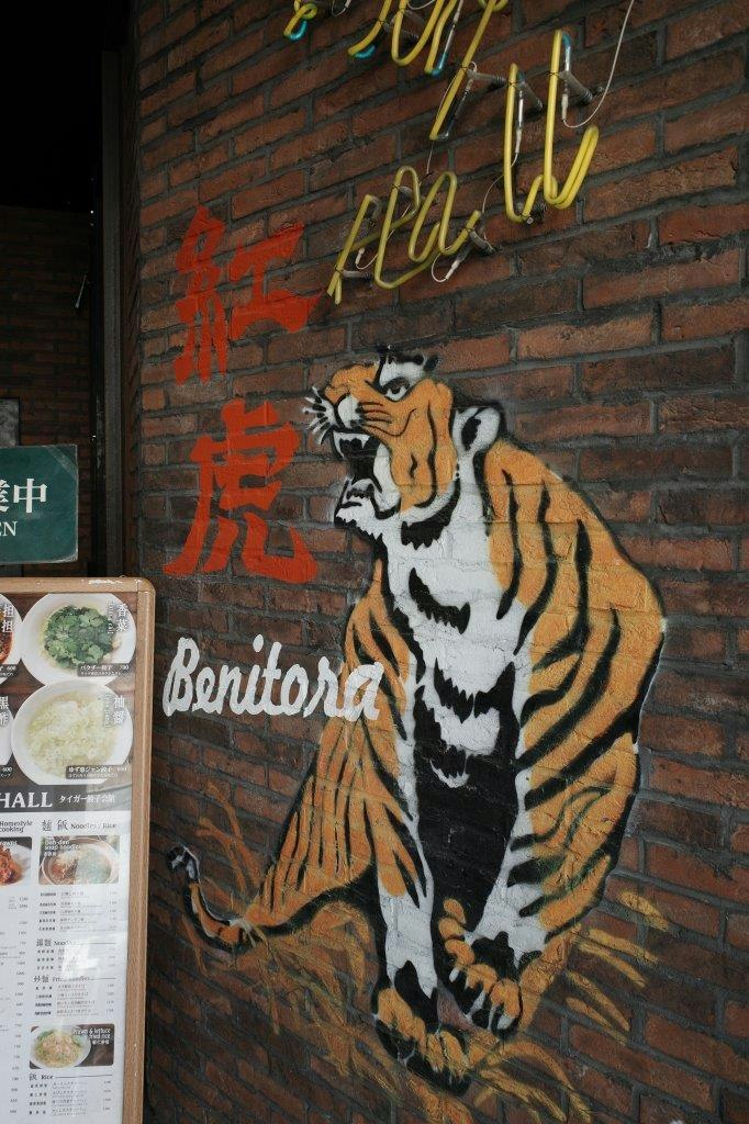 砖墙上的虎壁画与店铺招牌的街景