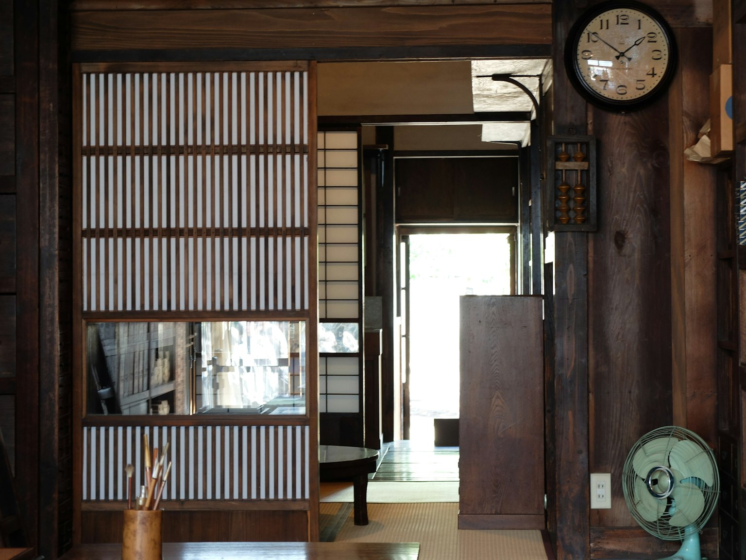 Intérieur d'une maison japonaise traditionnelle avec des portes coulissantes en bois une horloge et un ventilateur rétro