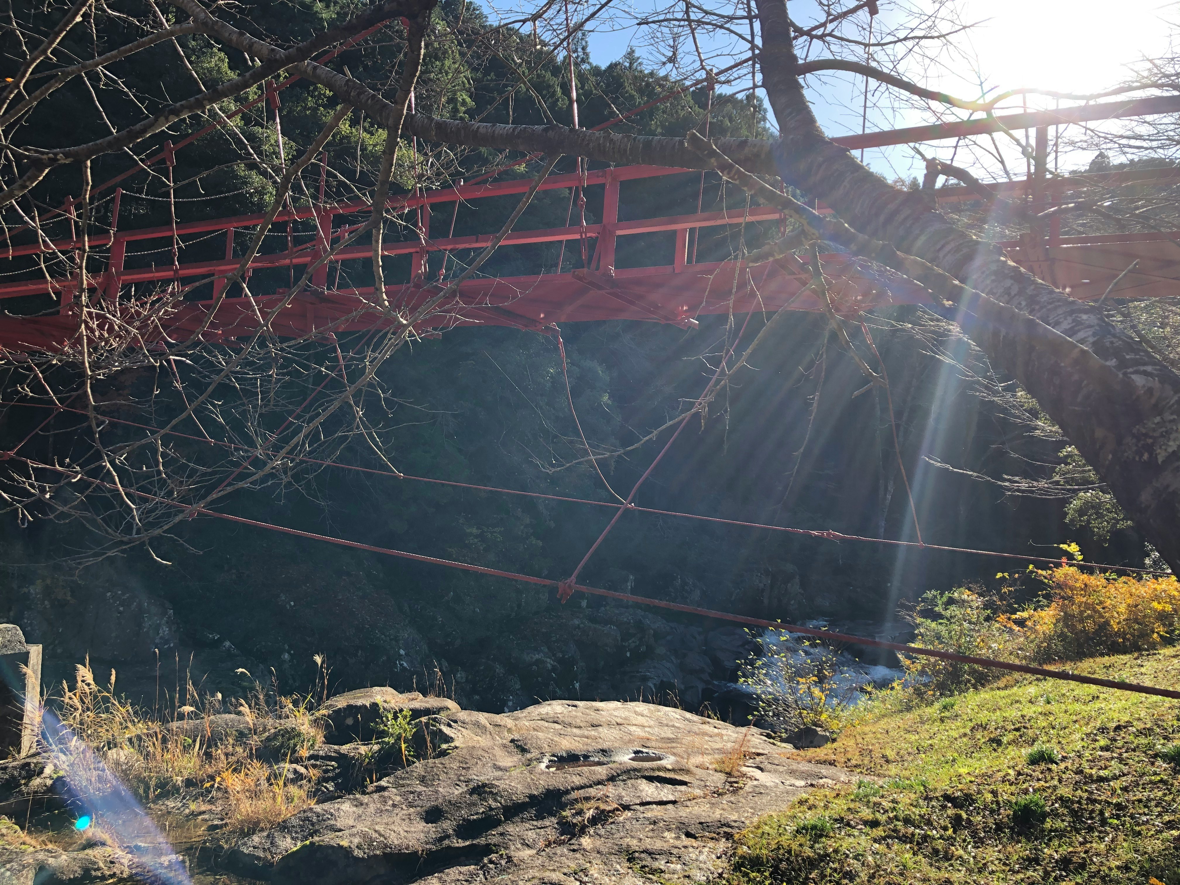 valley landscape with rocky riverbank and a red bridge