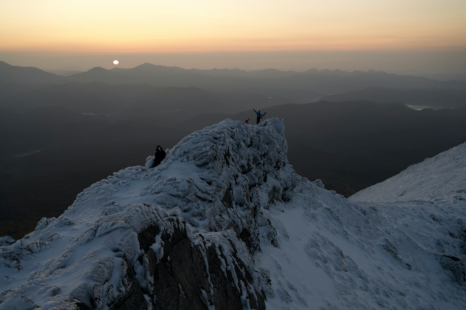 Pendaki di puncak gunung bersalju saat matahari terbit