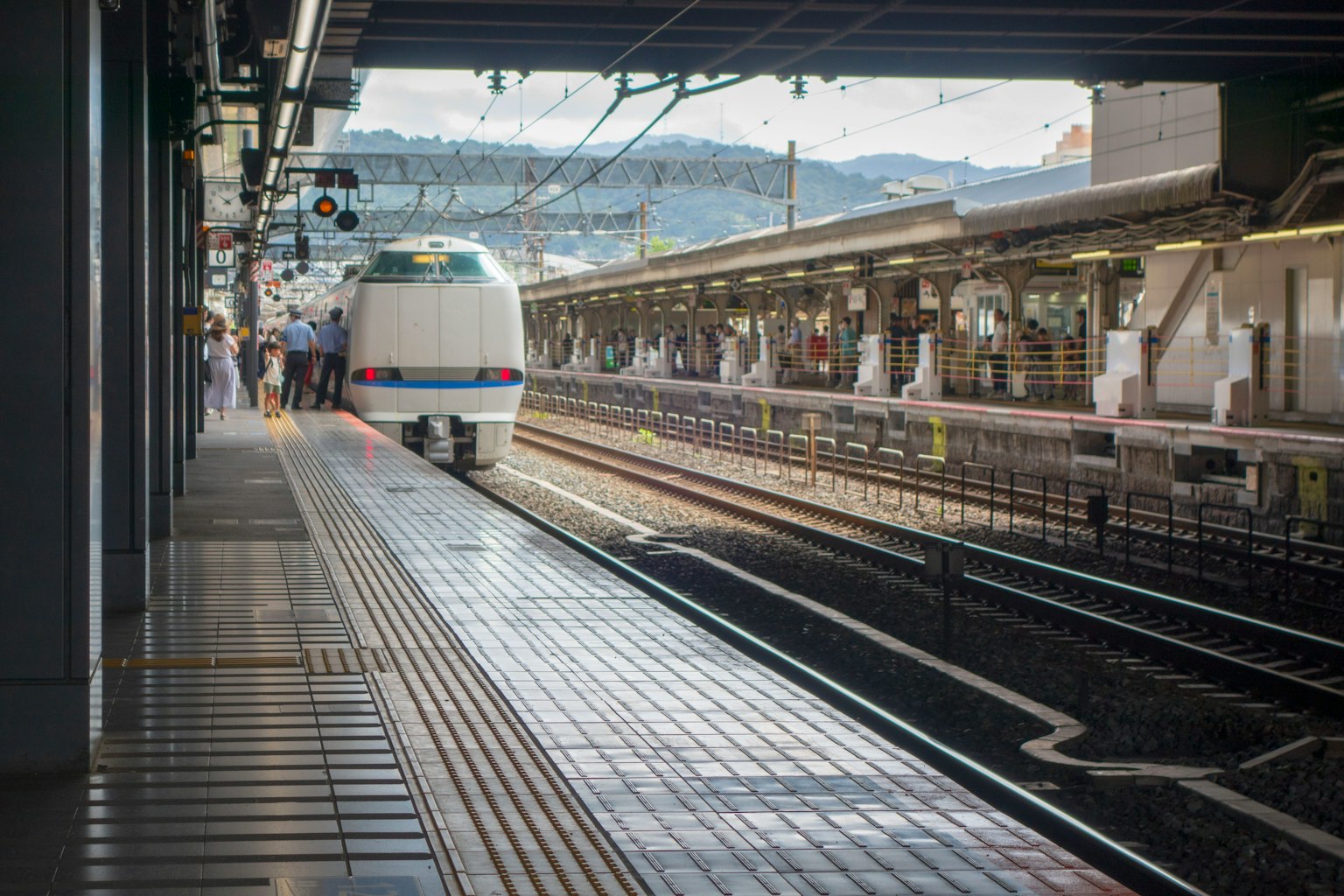 Vue d'une plateforme avec un train Shinkansen arrivant à une gare