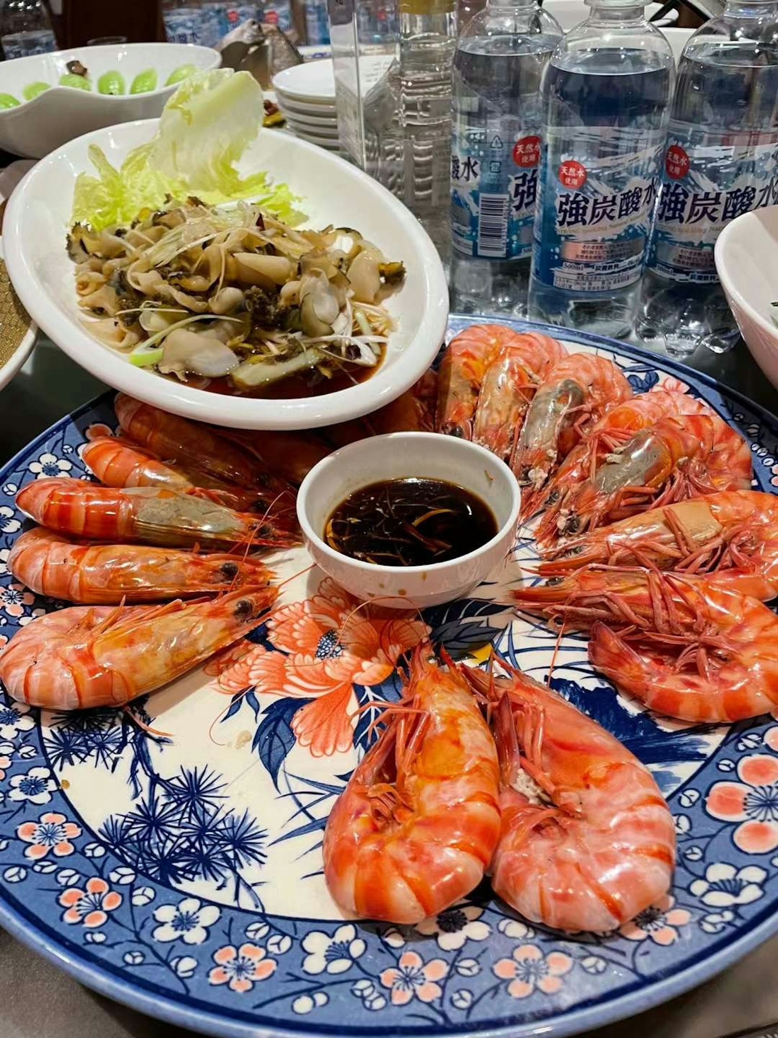 จานกุ้งหลากสีที่จัดเรียงอย่างสวยงามและจานผักข้างๆ