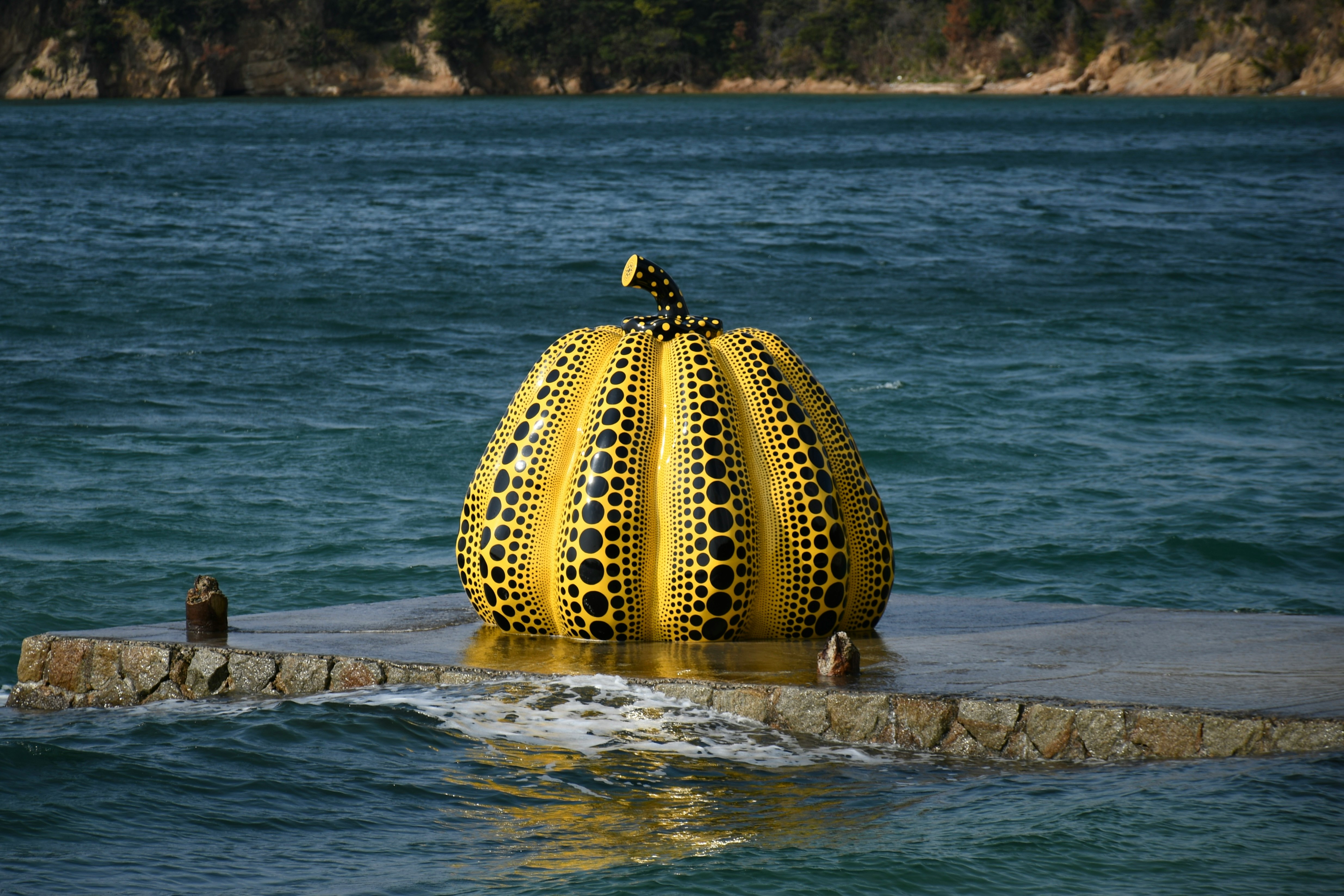 yellow pumpkin sculpture on rocks by the sea