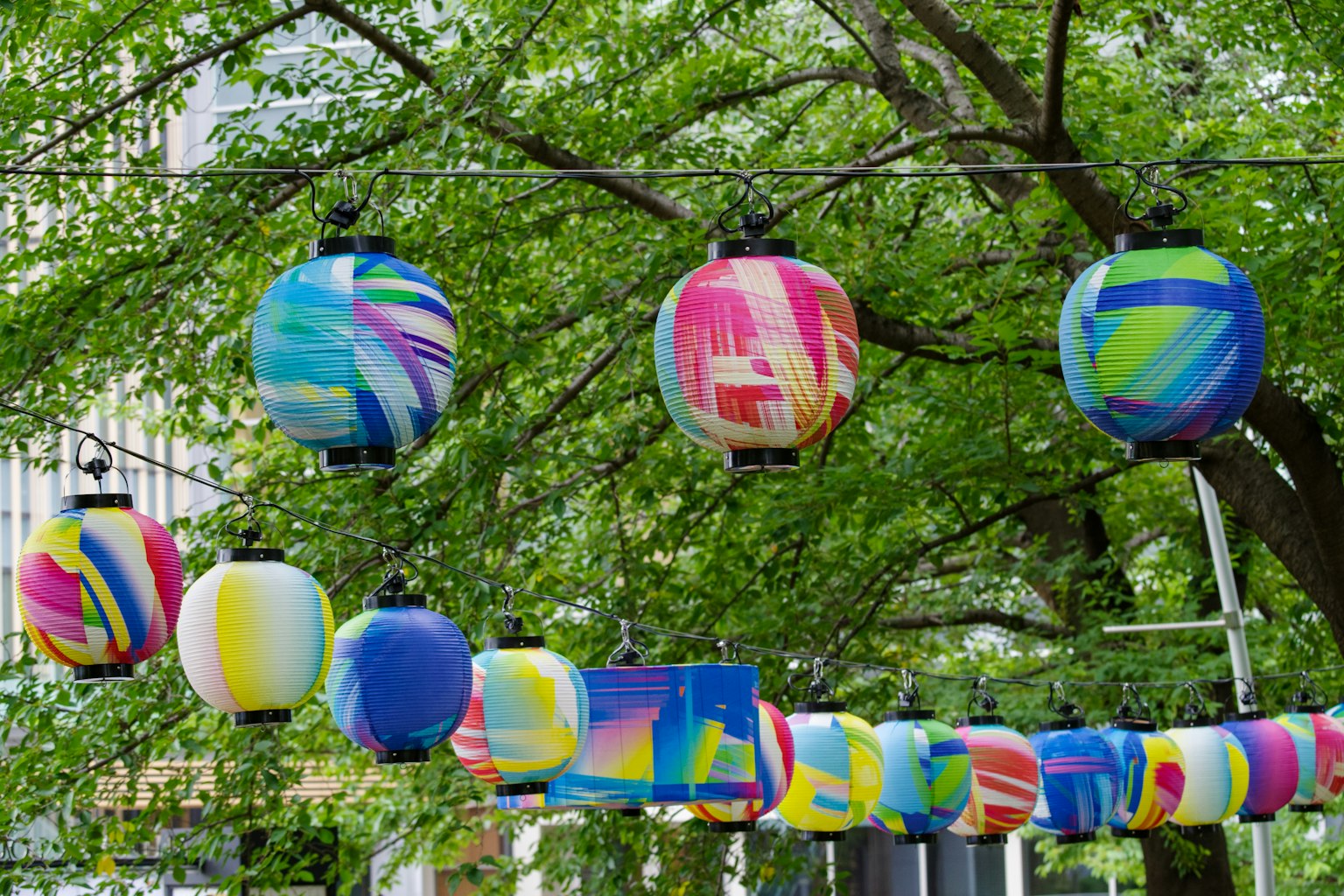 Colorful lanterns hanging between trees in a vibrant setting