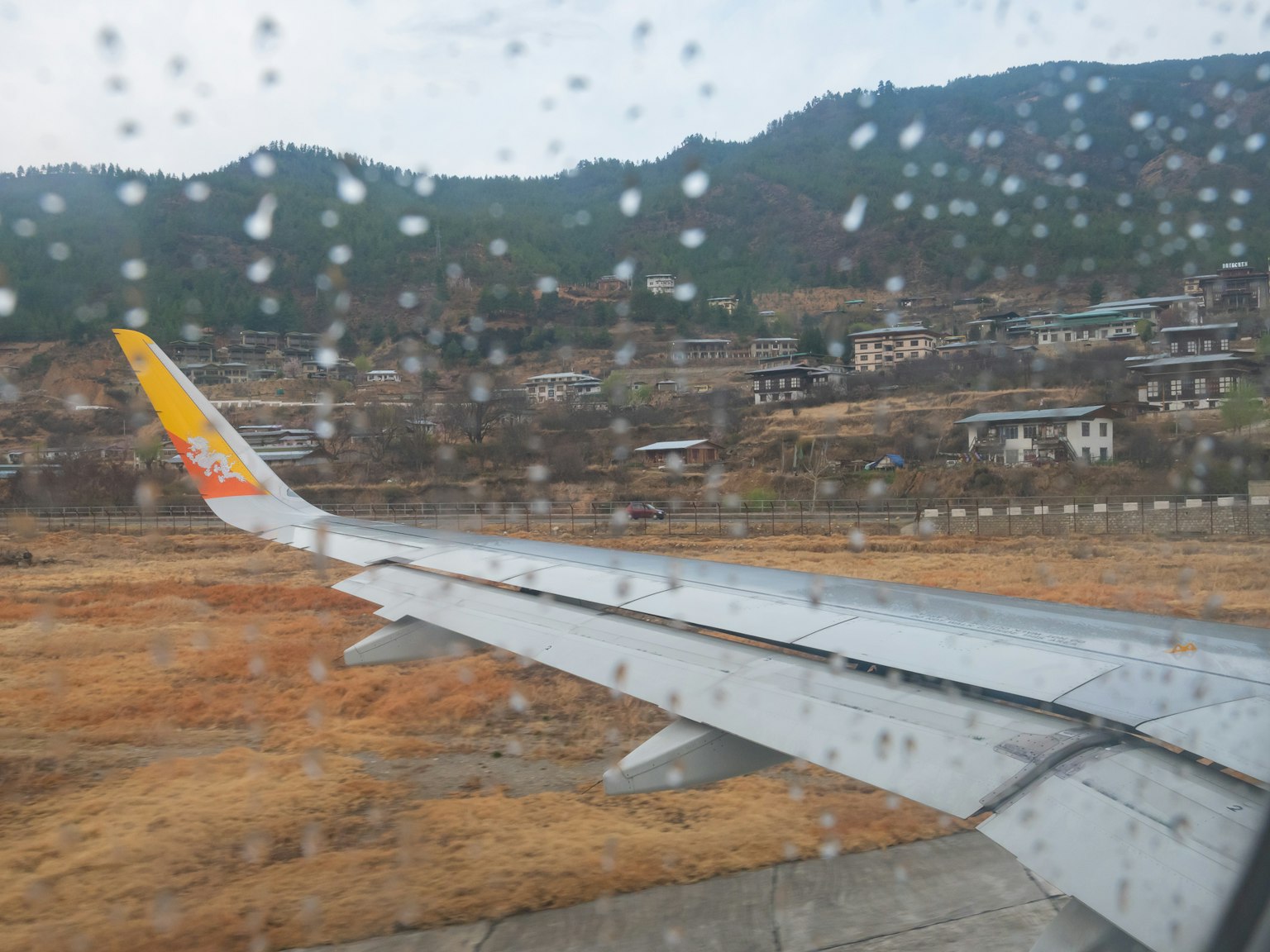 飞机翼与窗户上的雨滴展示的山区景观