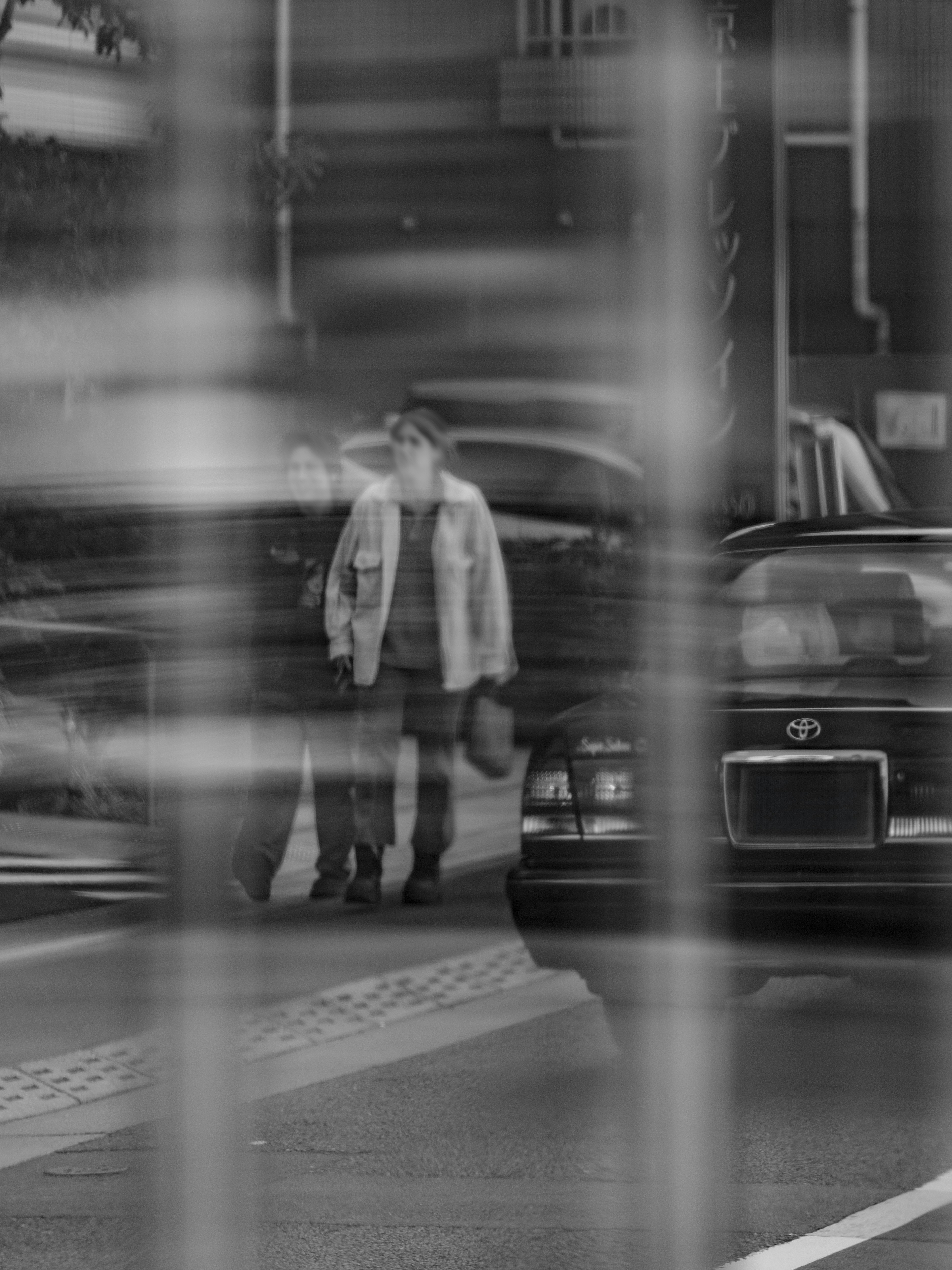 ガラス越しの街角で歩く人とタクシー