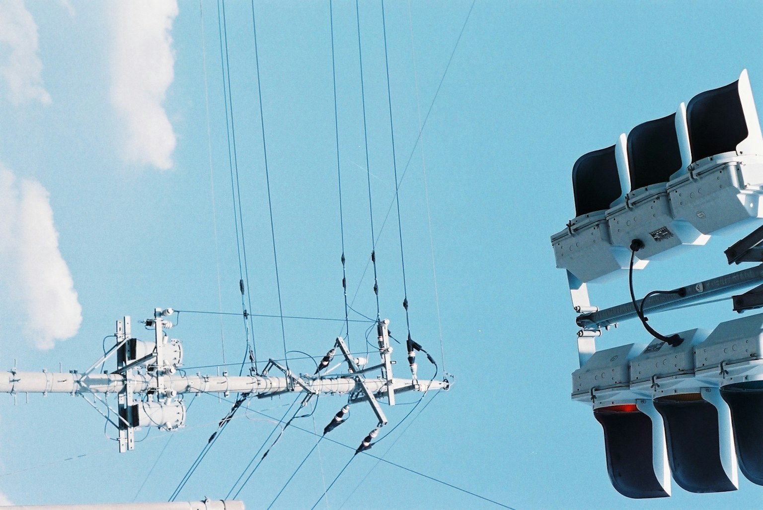 Una vista di un palo elettrico bianco e di un semaforo contro un cielo azzurro