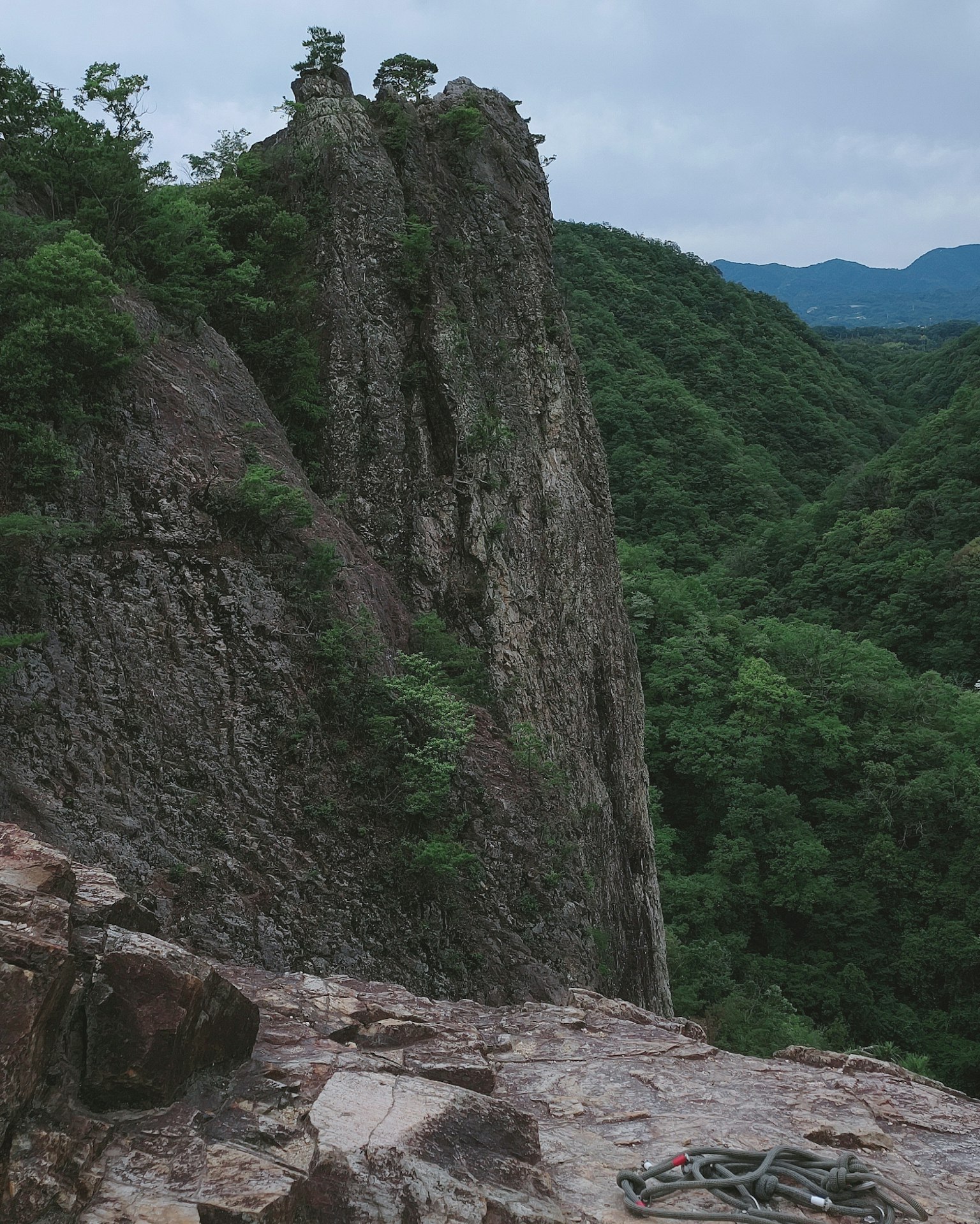 Pointe rocheuse abrupte entourée de montagnes verdoyantes