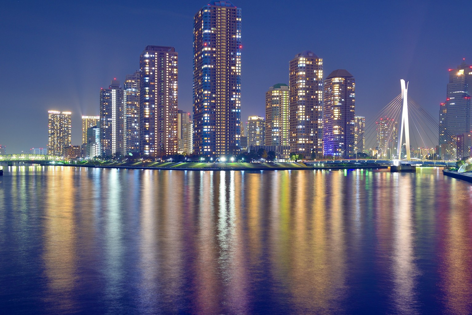 Vue nocturne de gratte-ciels se reflétant sur l'eau