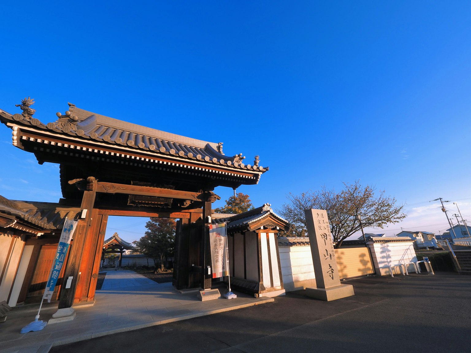 Pintu kuil Jepang tradisional dan monumen batu di bawah langit biru yang cerah