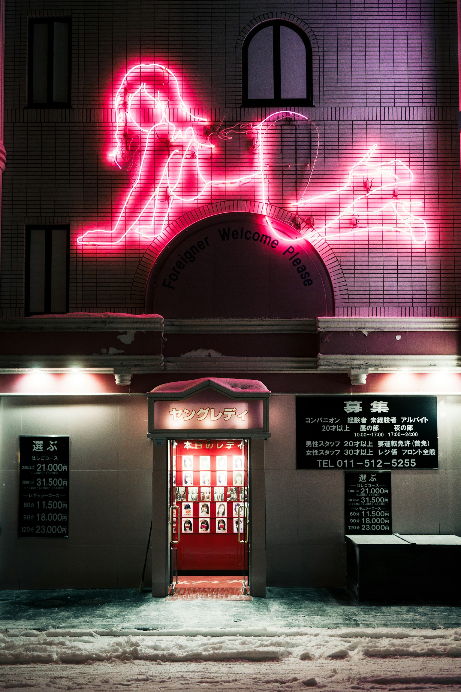 Gebäudefassade mit auffälligem pinkem Neonzeichen, das die Silhouette einer Frau zeigt