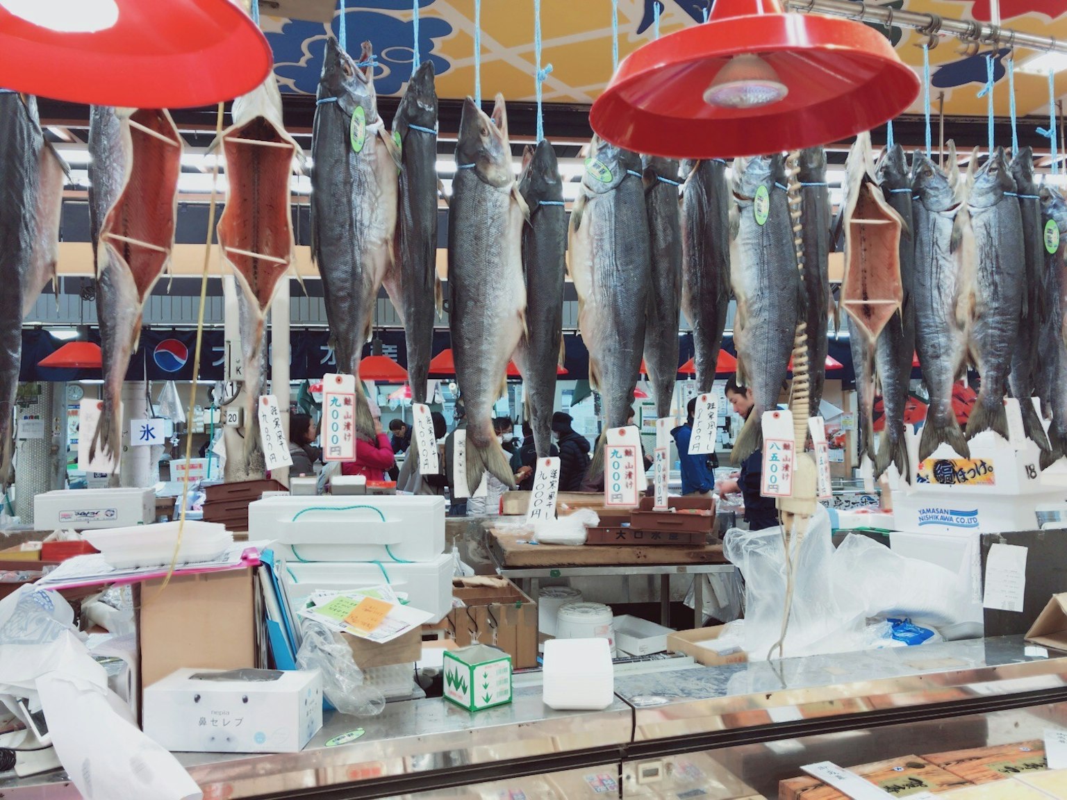 魚市場的場景，懸掛的魚和各種包裝可見