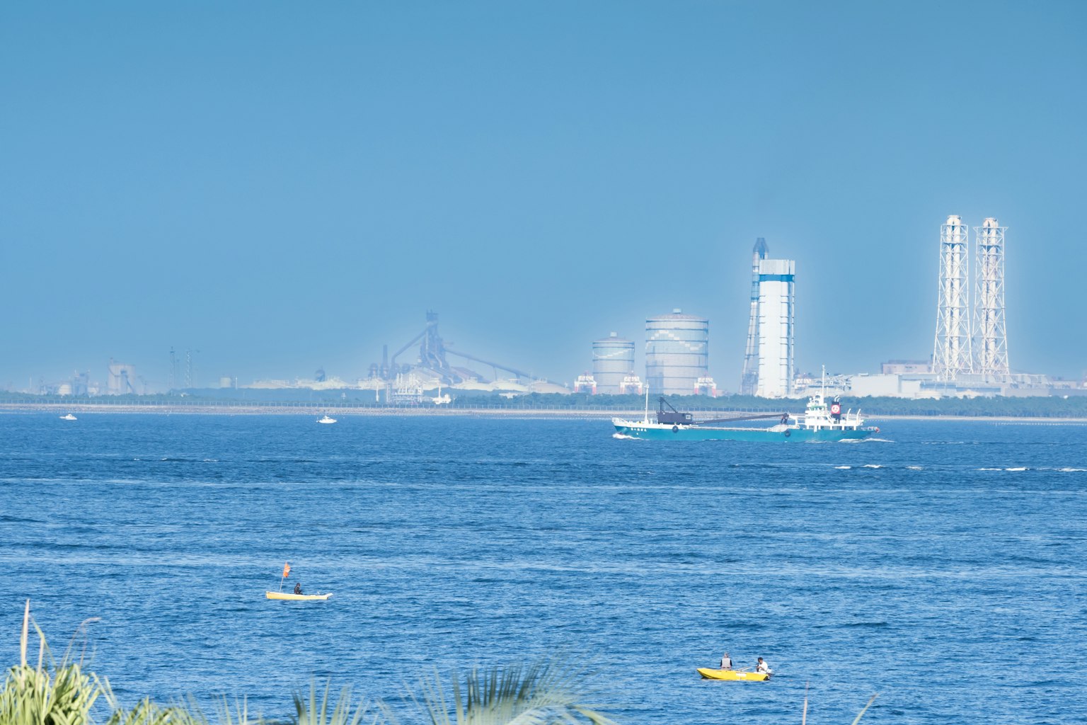 Vista escénica del mar azul con edificios altos al fondo y un barco navegando