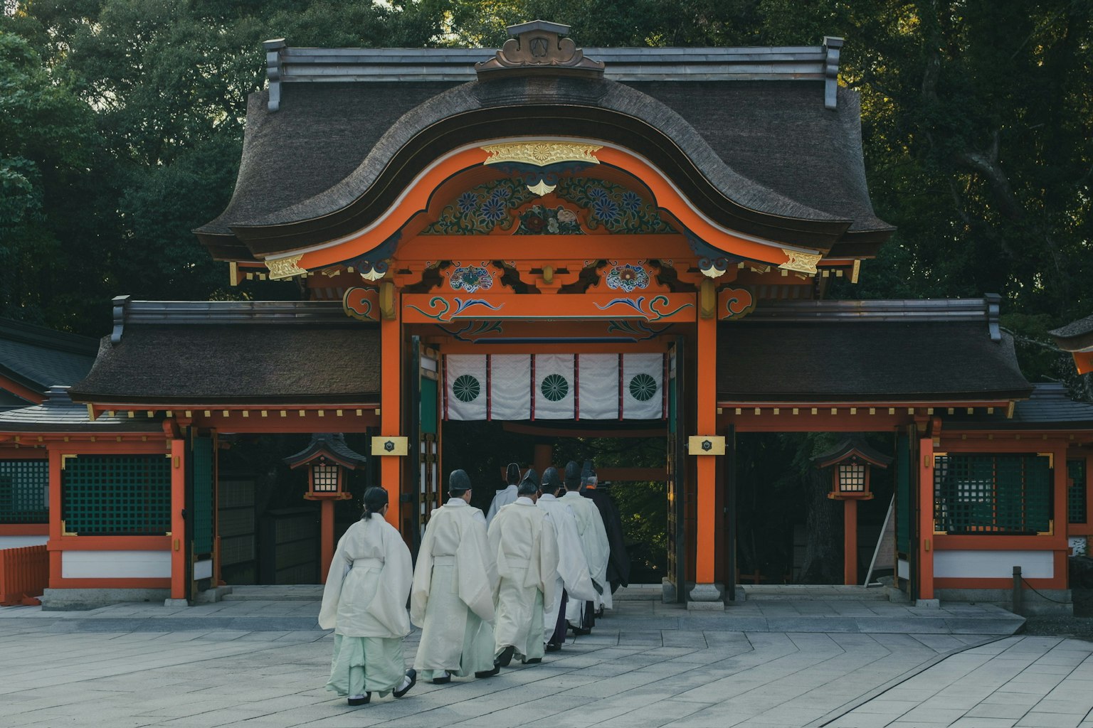 神社の前で白い衣装を着た人々が行進している様子