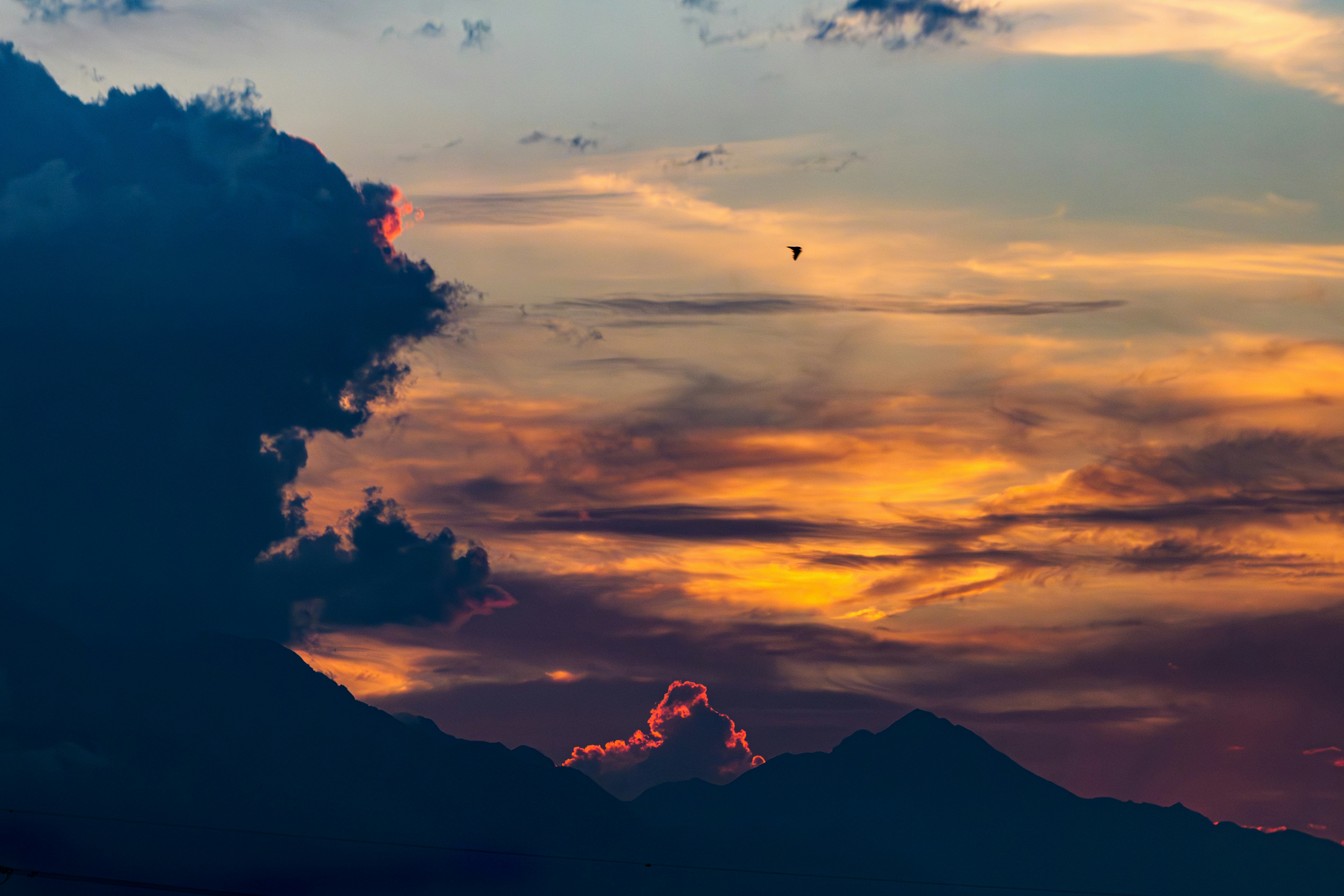 silhuetas de montañas bajo un cielo de atardecer con nubes