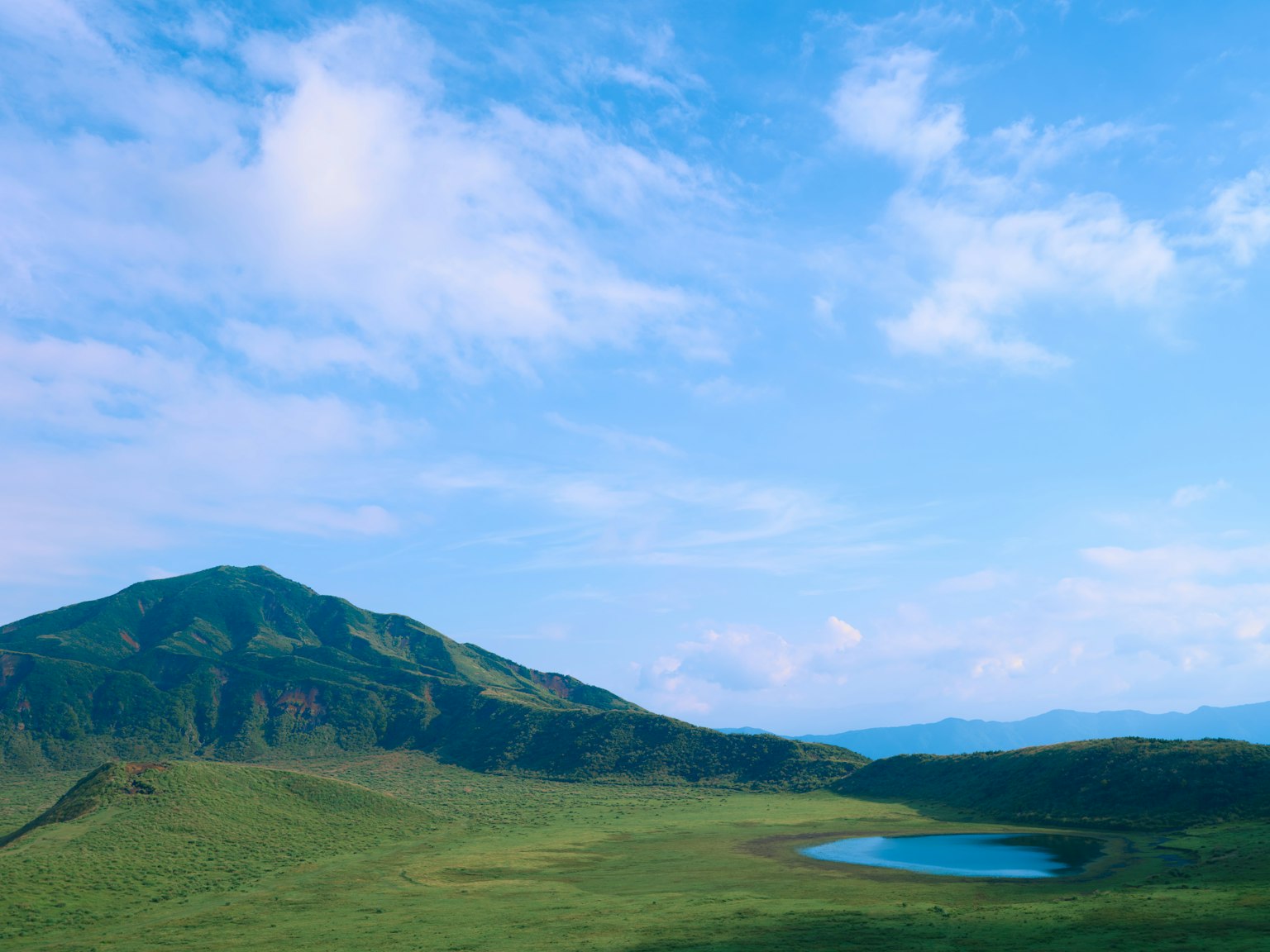Pemandangan gunung dengan padang rumput hijau dan danau biru