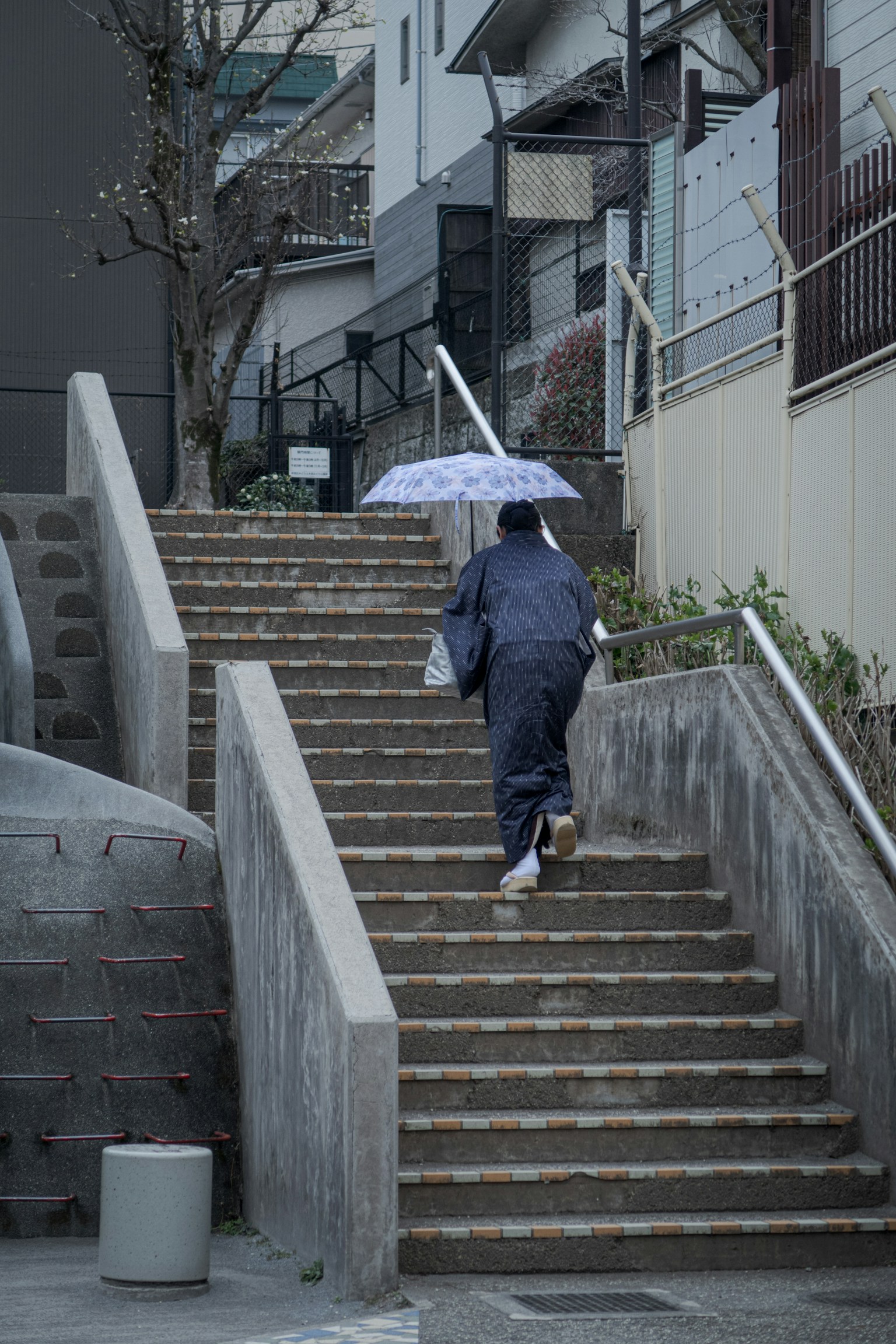 Person holding an umbrella walking up stairs