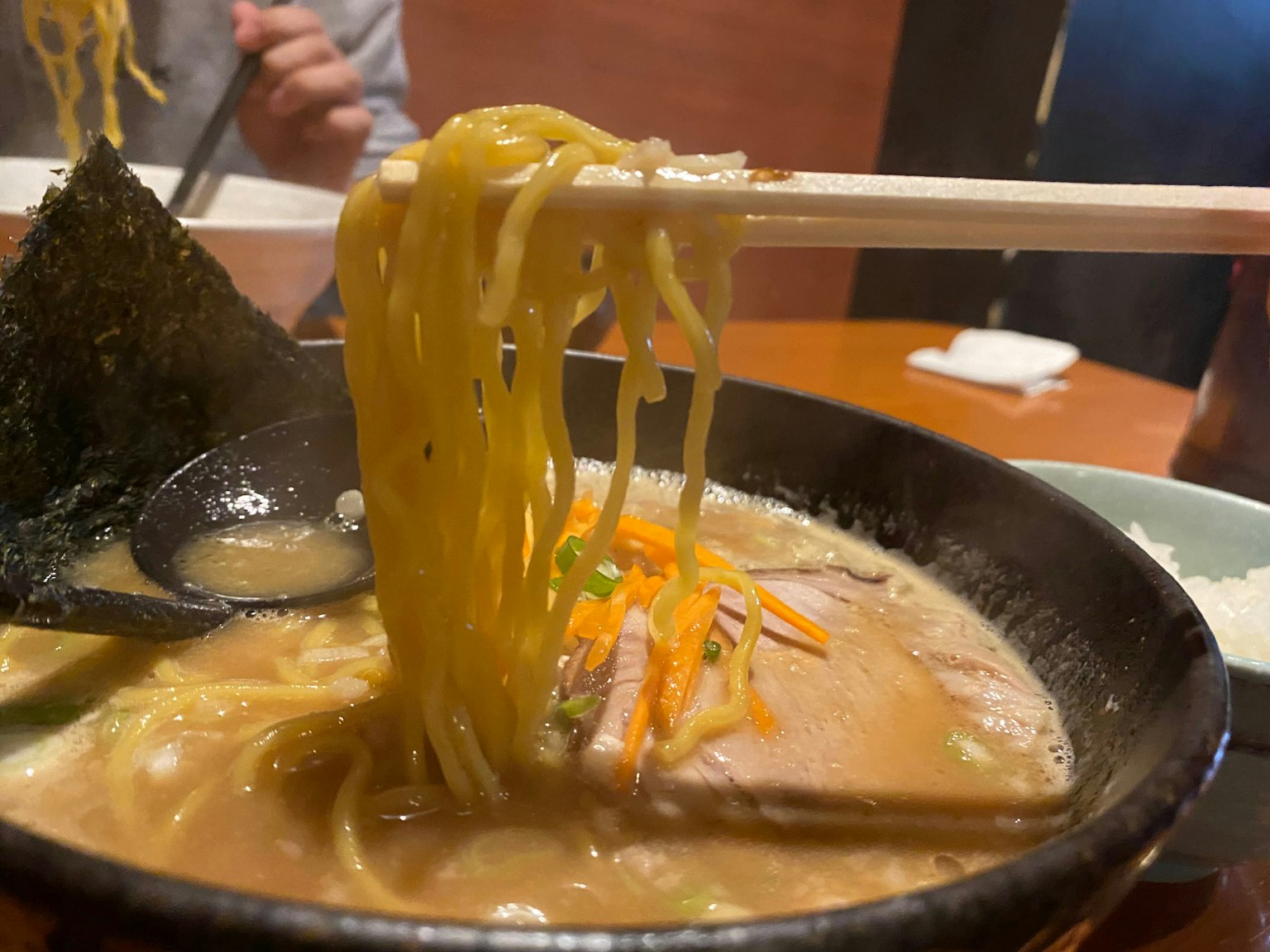 톤코츠 라멘 그릇에 얇은 면과 다양한 토핑이 담겨 있다