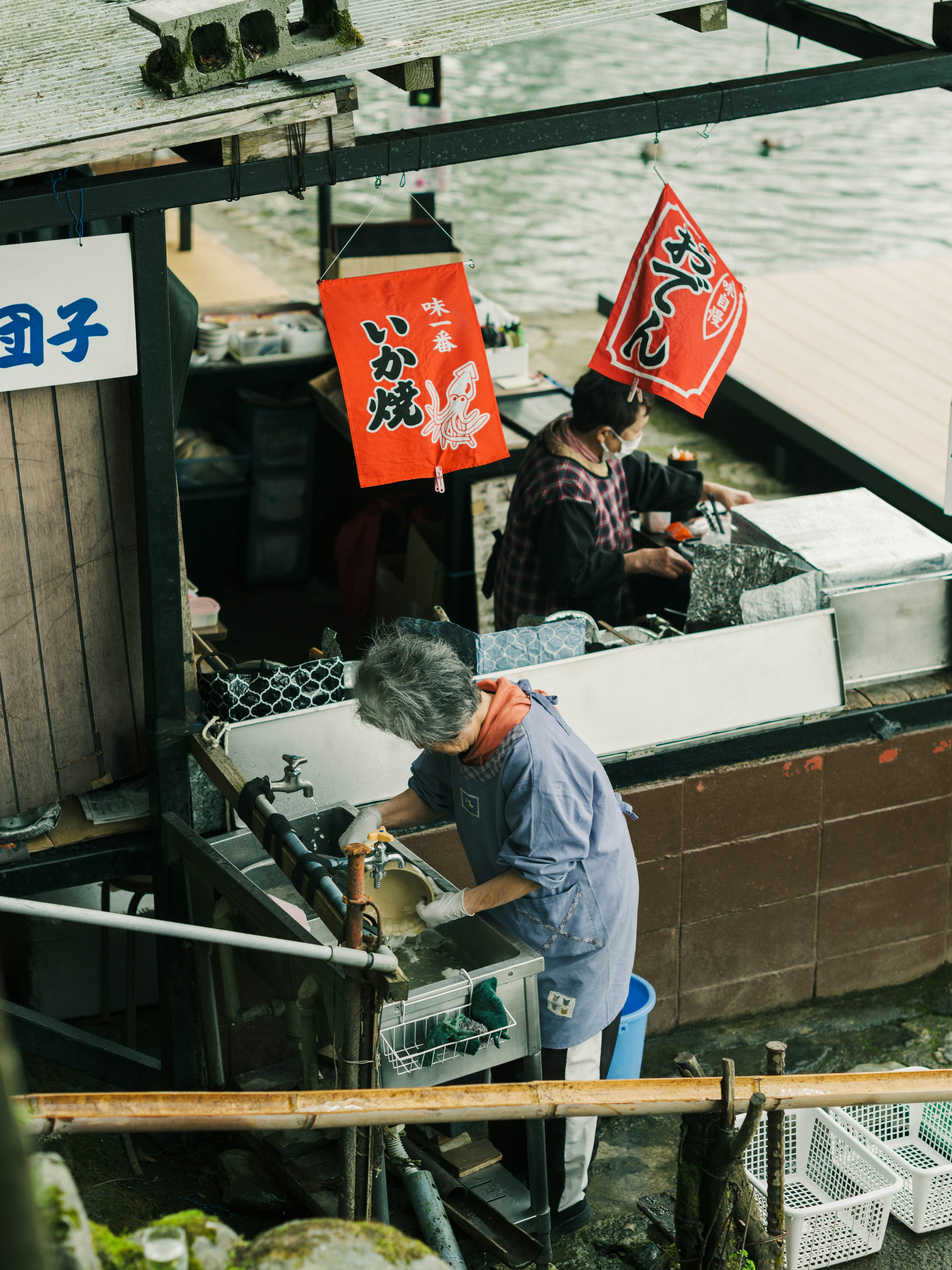 屋台のような店先で働く人々とのぼりのある風景