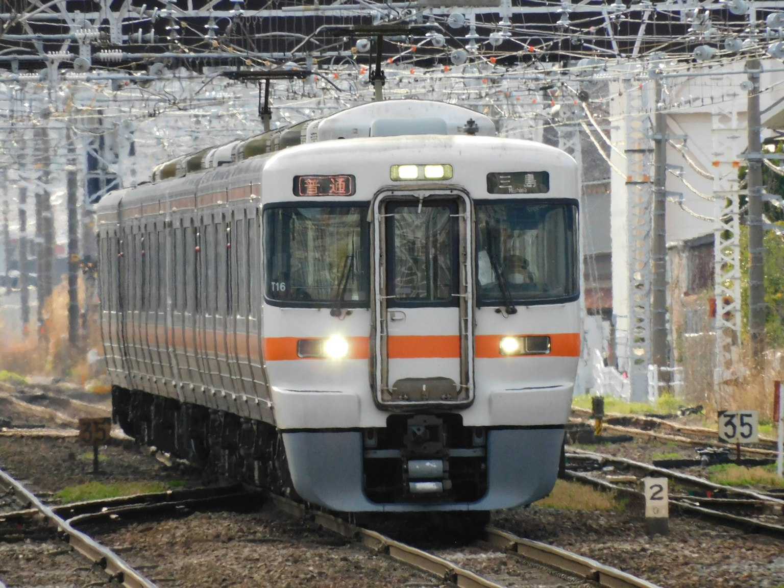 Un train blanc avec des rayures orange circulant sur les rails