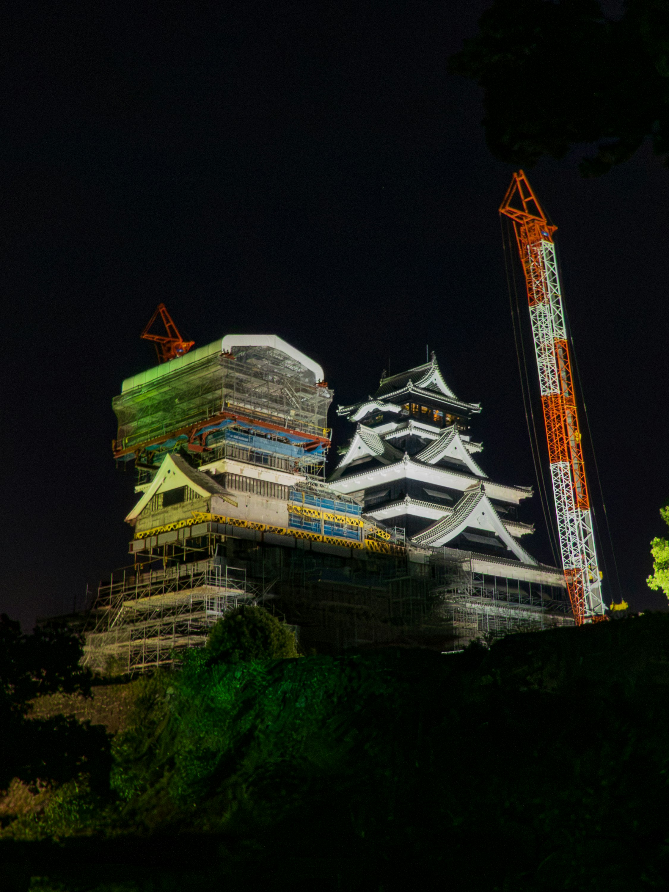 Notte a Kumamoto: il mastio del castello di Kumamoto illuminato con ponteggi di restauro