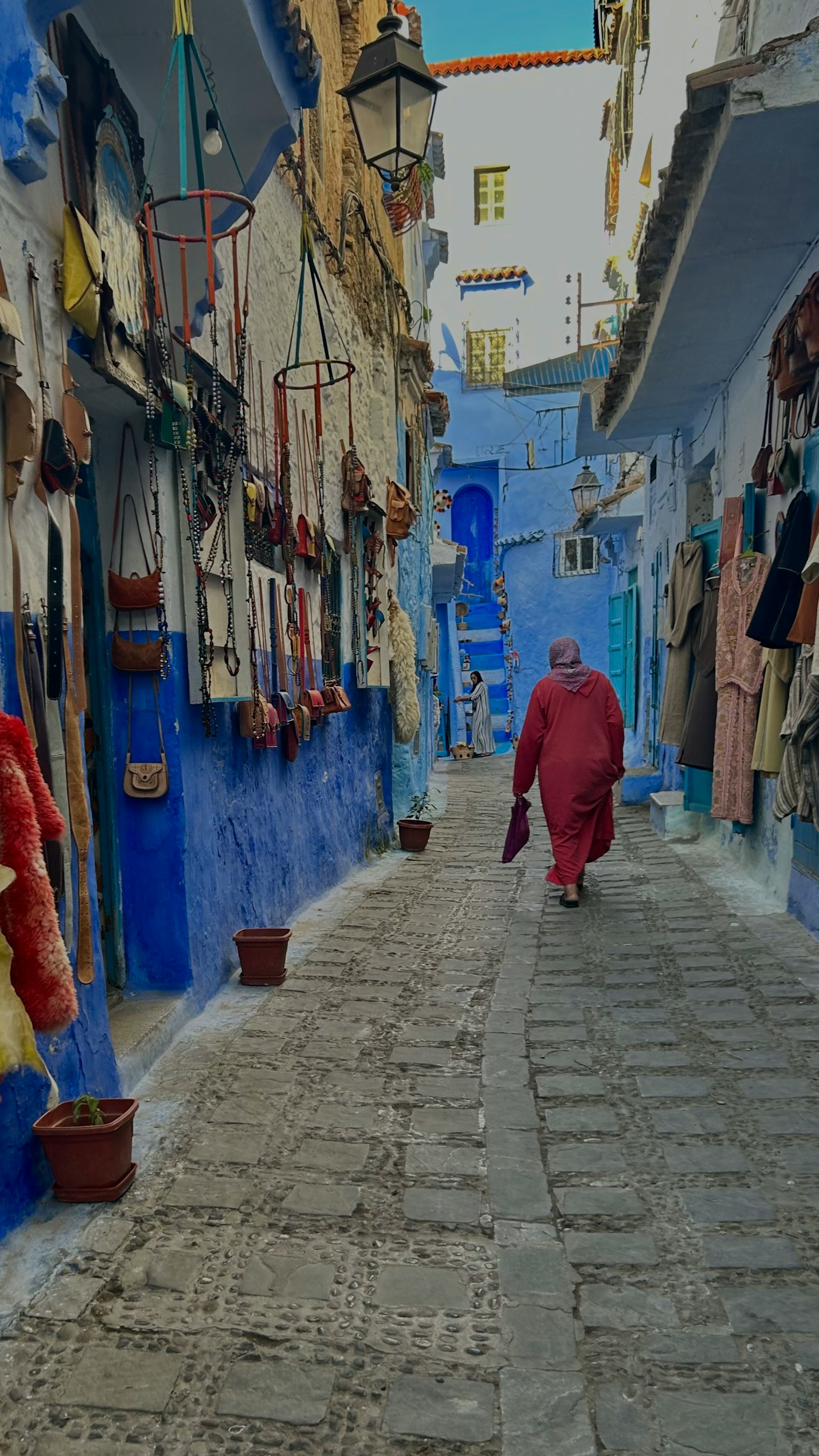 Eine Person in roter Kleidung, die durch eine blaue Gasse geht