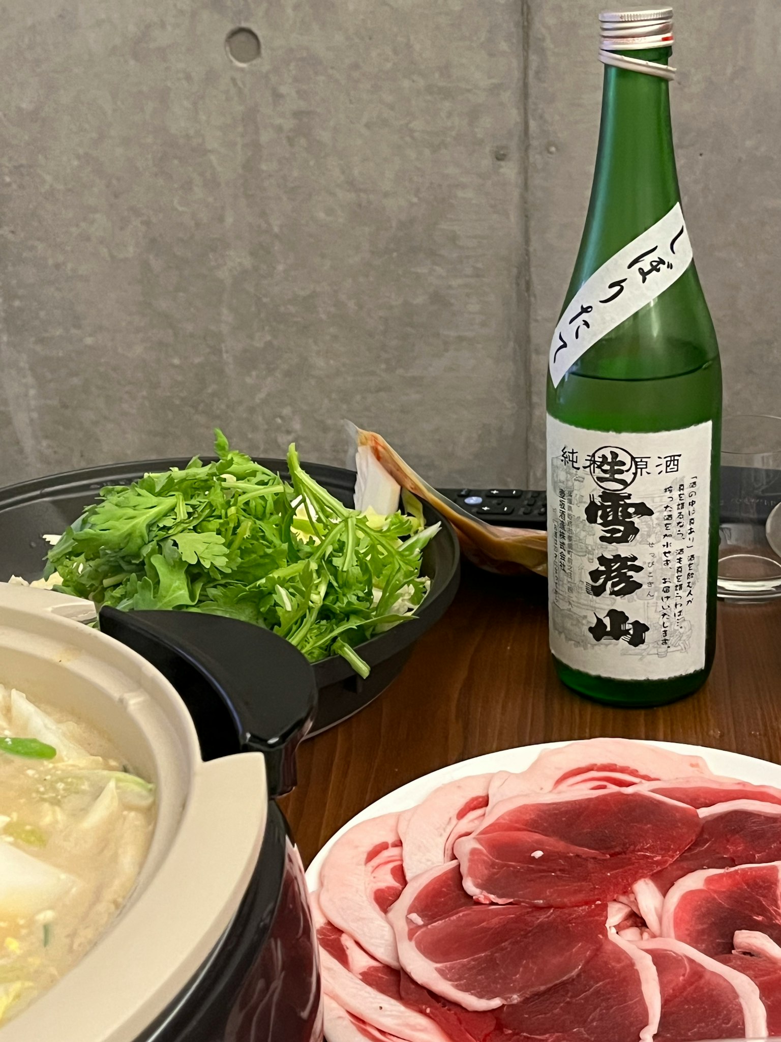 Tischanordnung mit Hot-Pot-Zutaten und Sake-Flasche