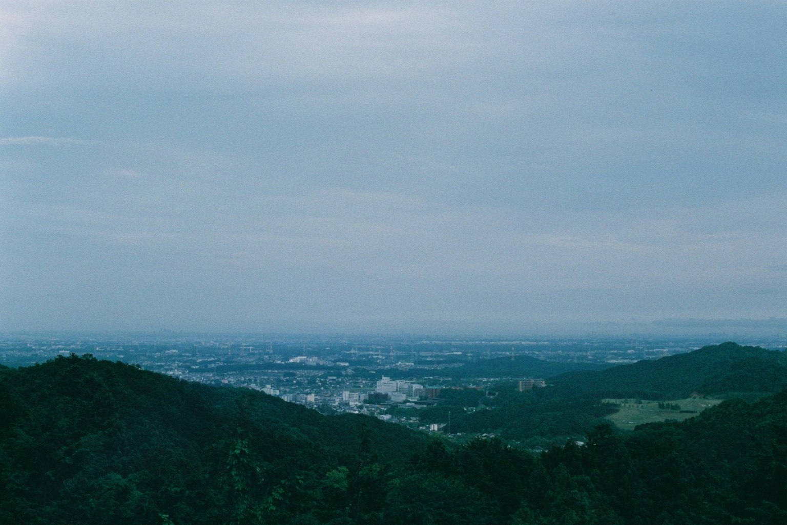 Berglandschaft mit Blick auf eine Stadt unter blauem Himmel und Wolken