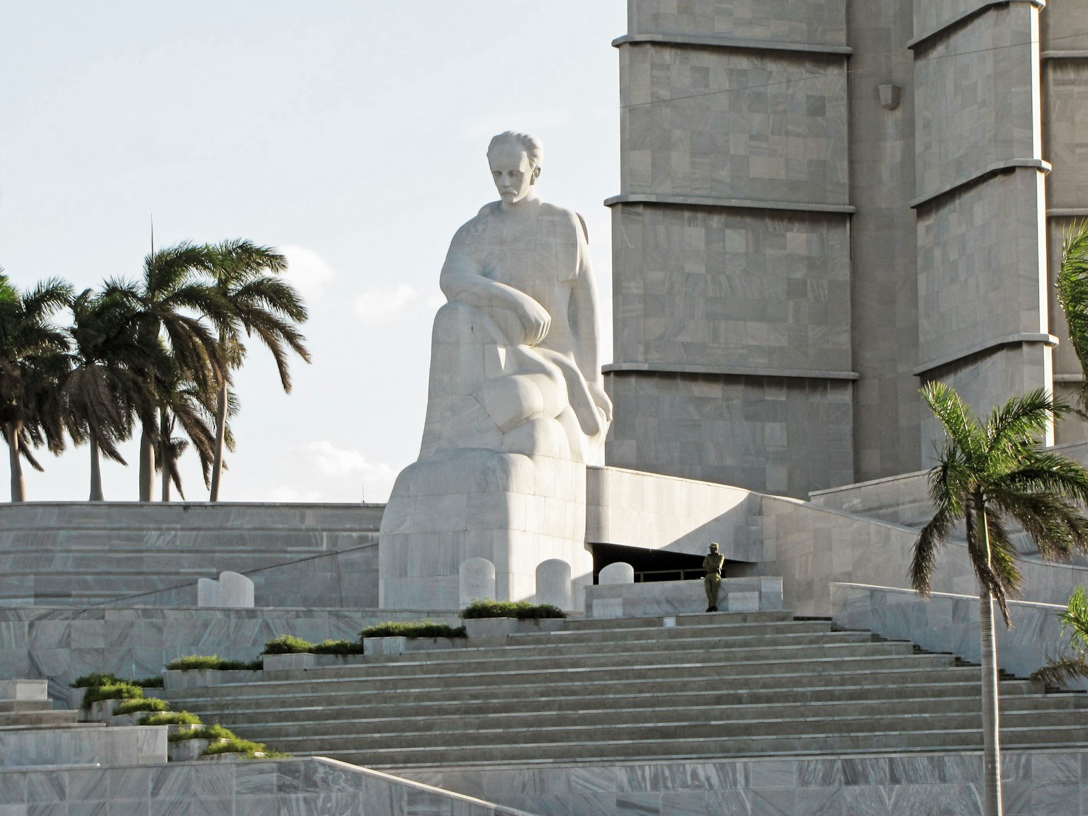 Una statua bianca prominente in una piazza circondata da palme