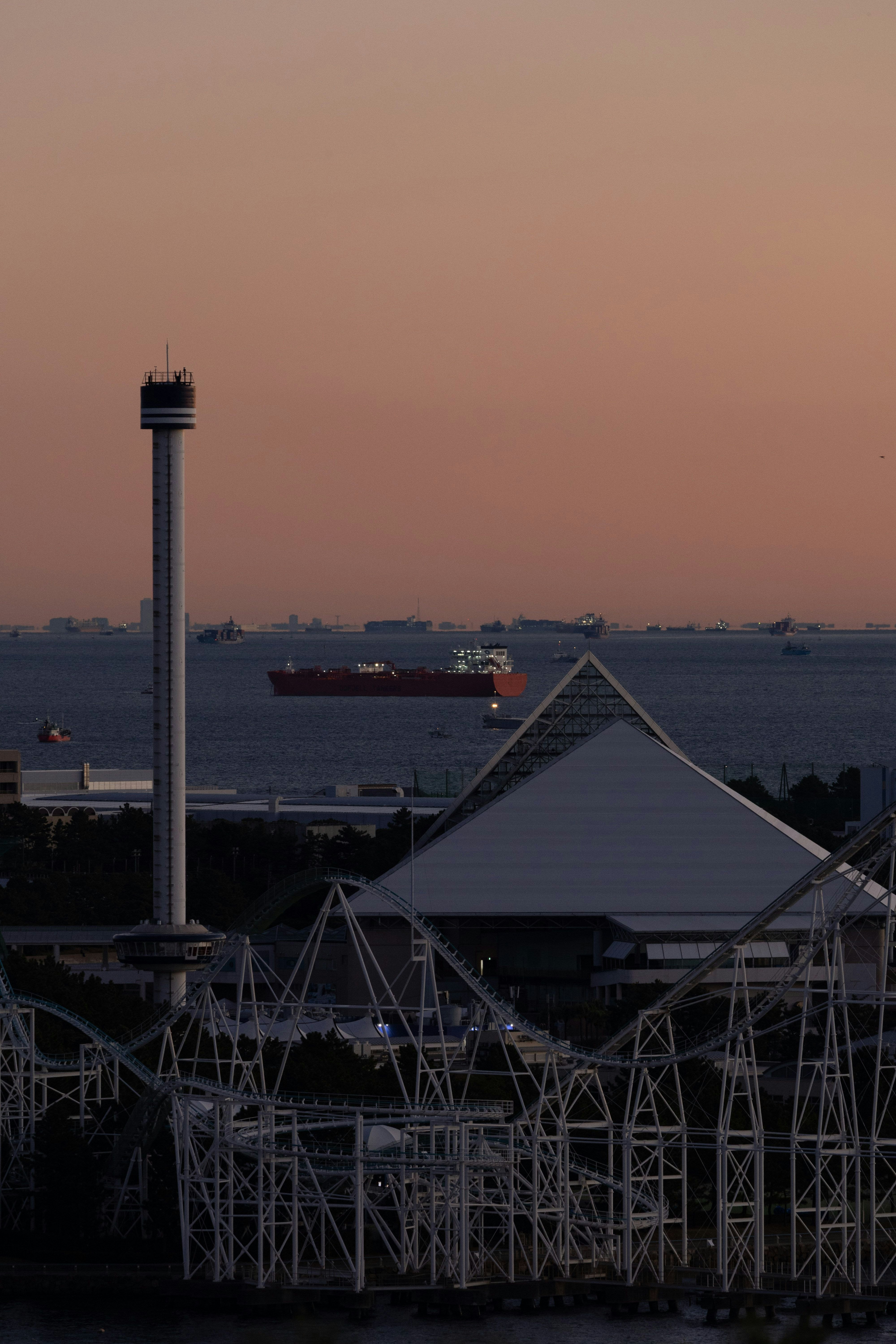 夕暮れの港と展望塔、遠景に船が浮かぶ