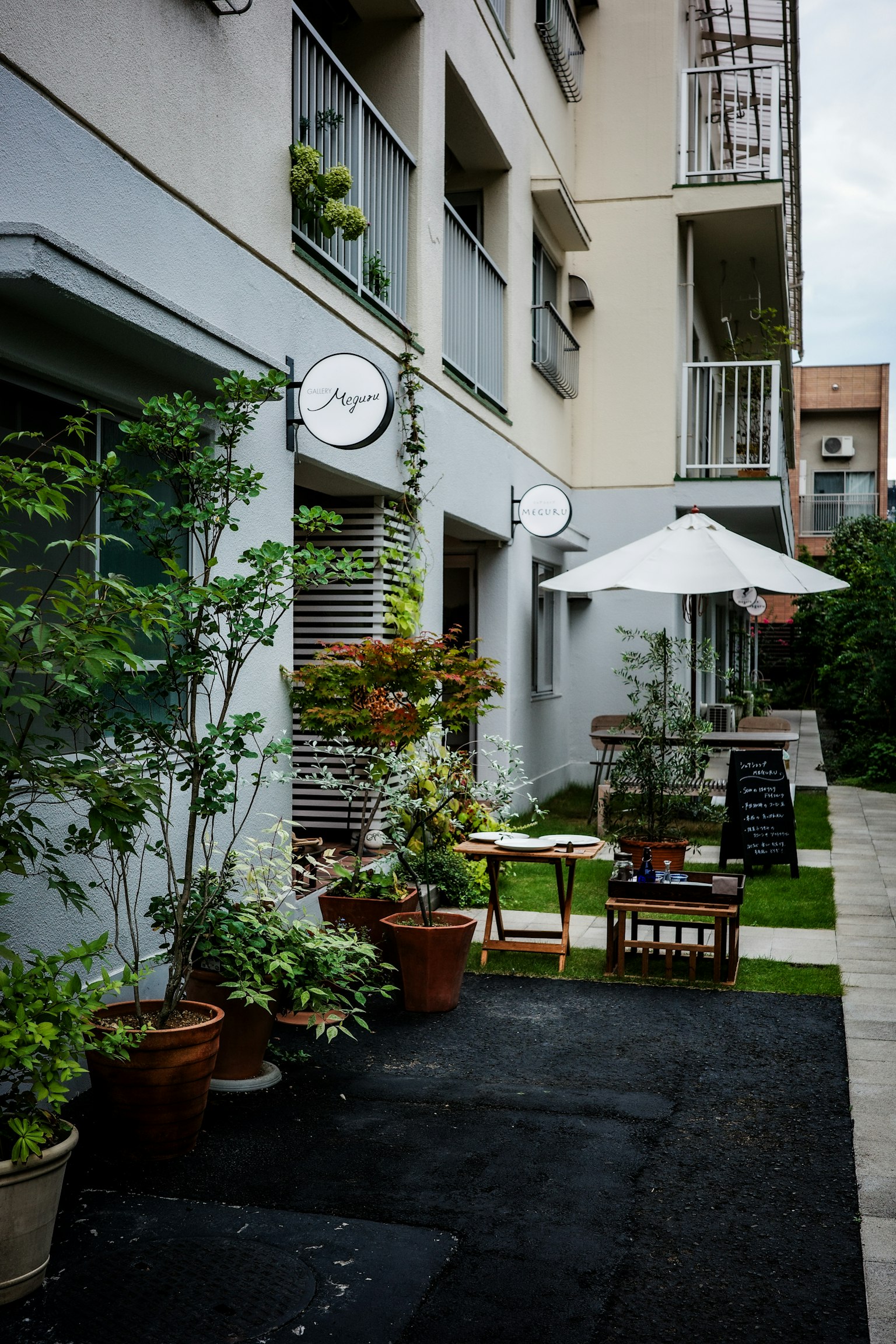 Extérieur de café charmant avec verdure et terrasse couverte d'un parasol