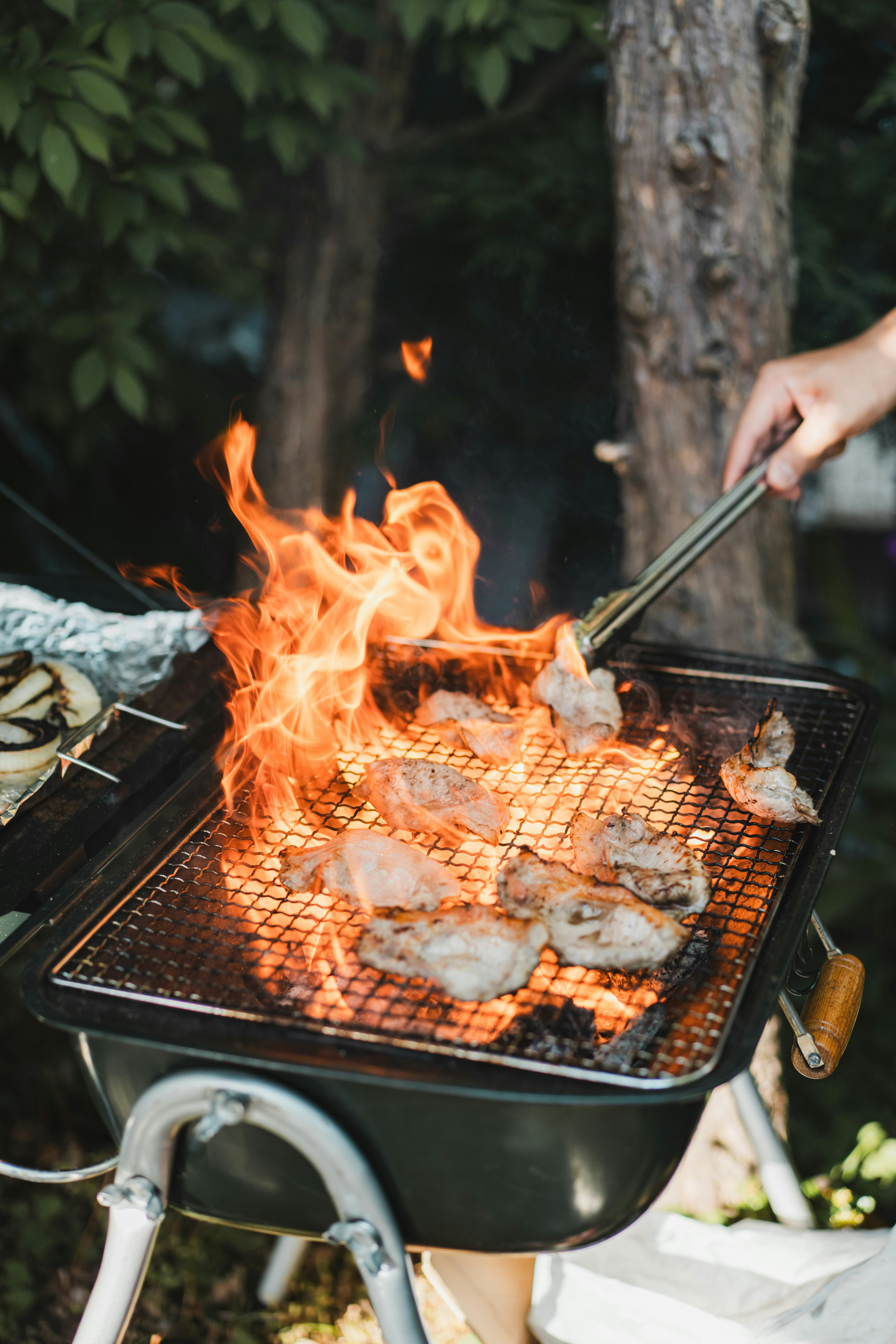 bếp nướng BBQ ngoài trời với ngọn lửa và thịt đang nướng
