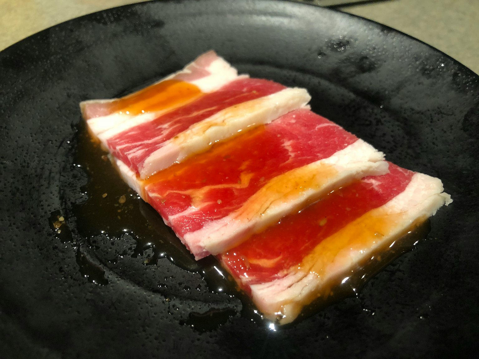 Fette di carne disposte su un piatto nero con strati colorati