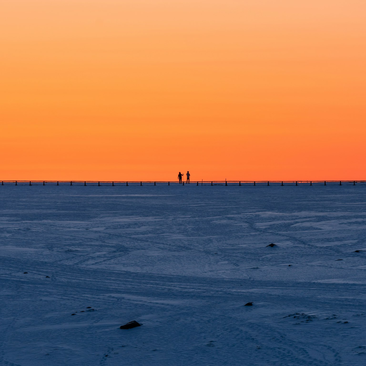 Silhouette di due persone sotto un tramonto arancione
