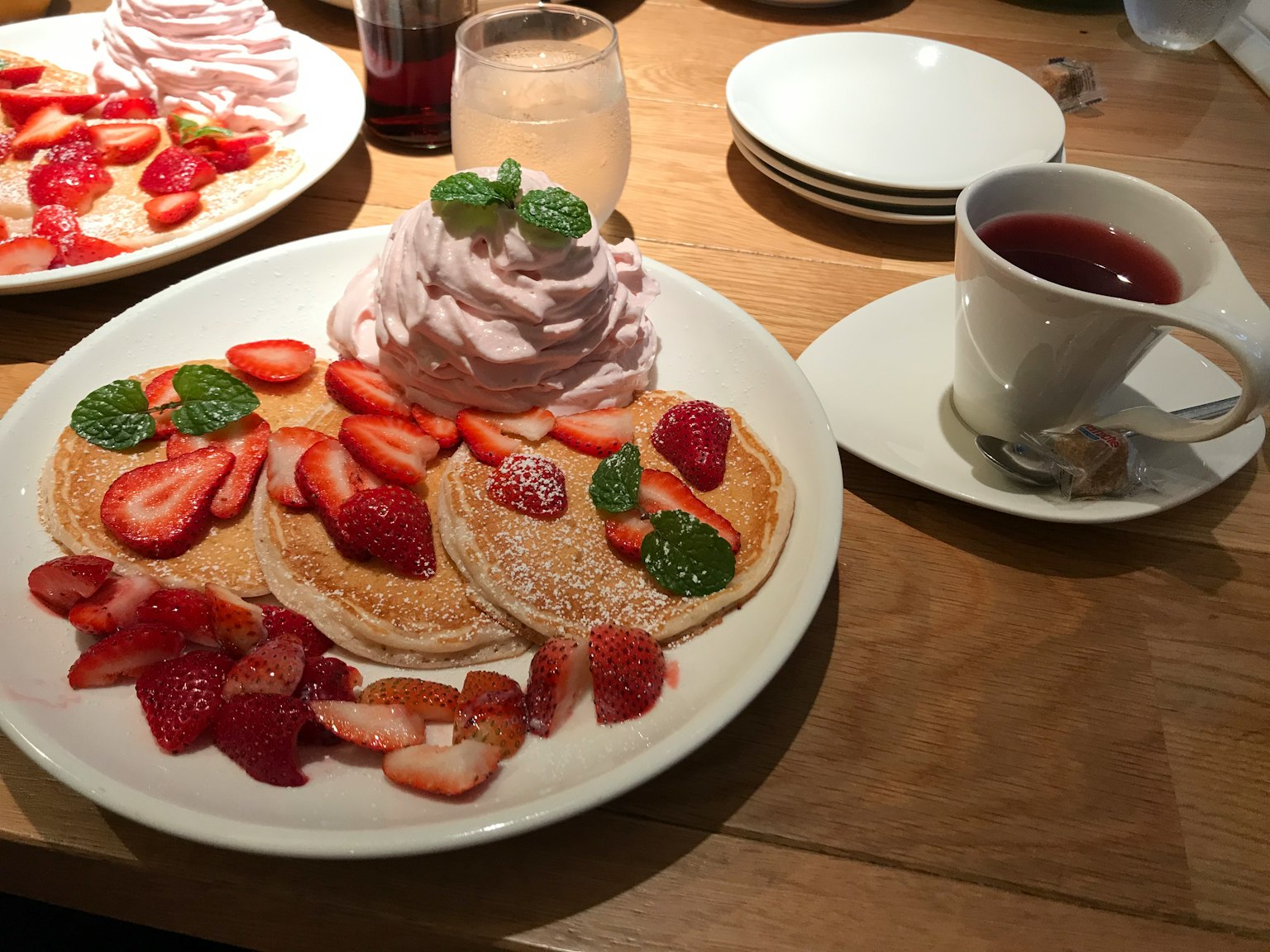 Pancakes délicieux garnis de fraises et de crème fouettée décorés de feuilles de menthe