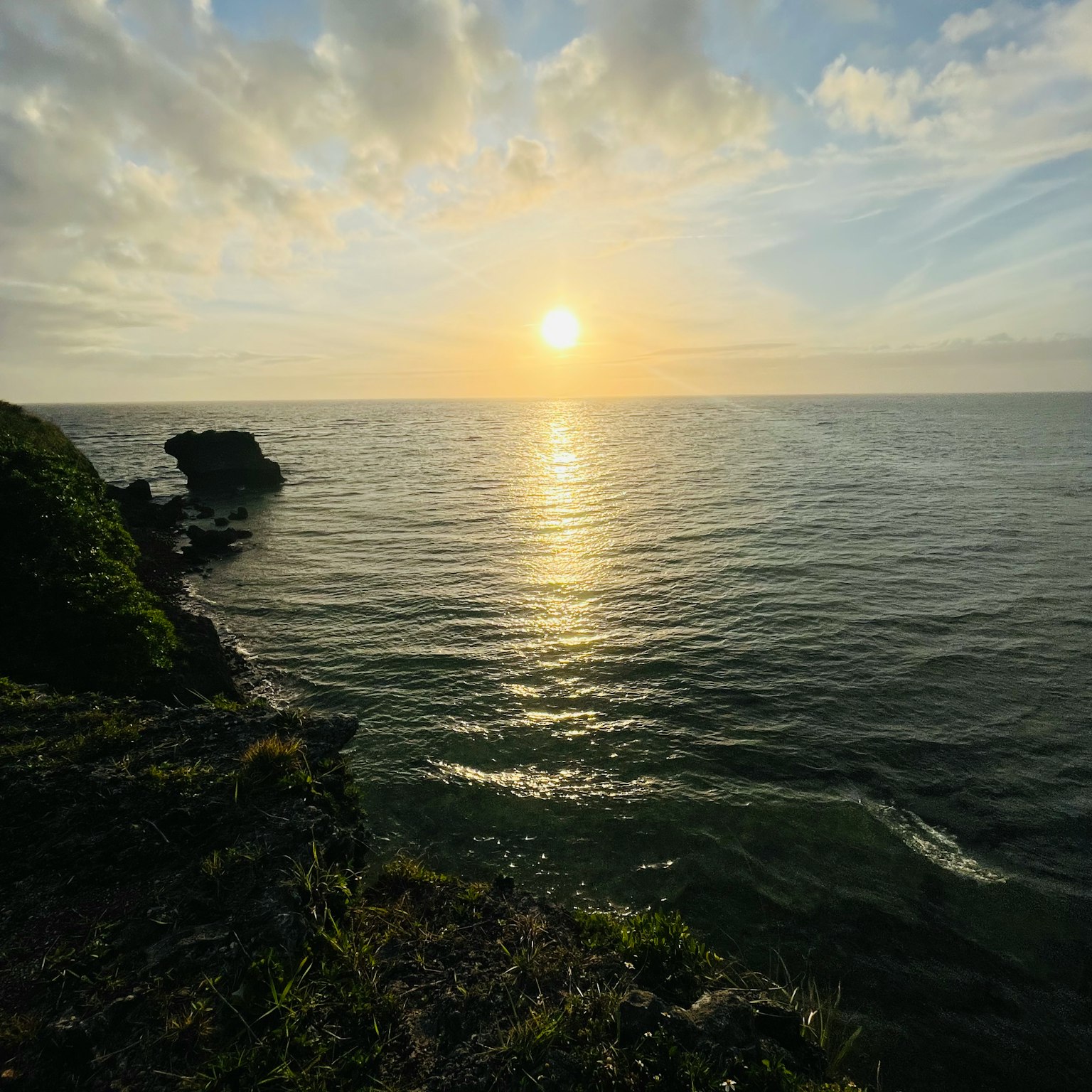 美丽的风景，夕阳映在海面上，从悬崖上的岩石和草地的视角