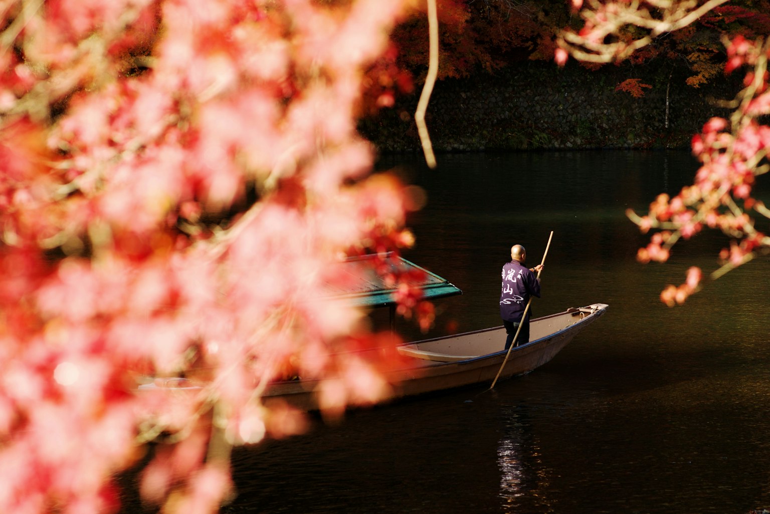 Hombre remando en un pequeño bote entre el follaje de otoño
