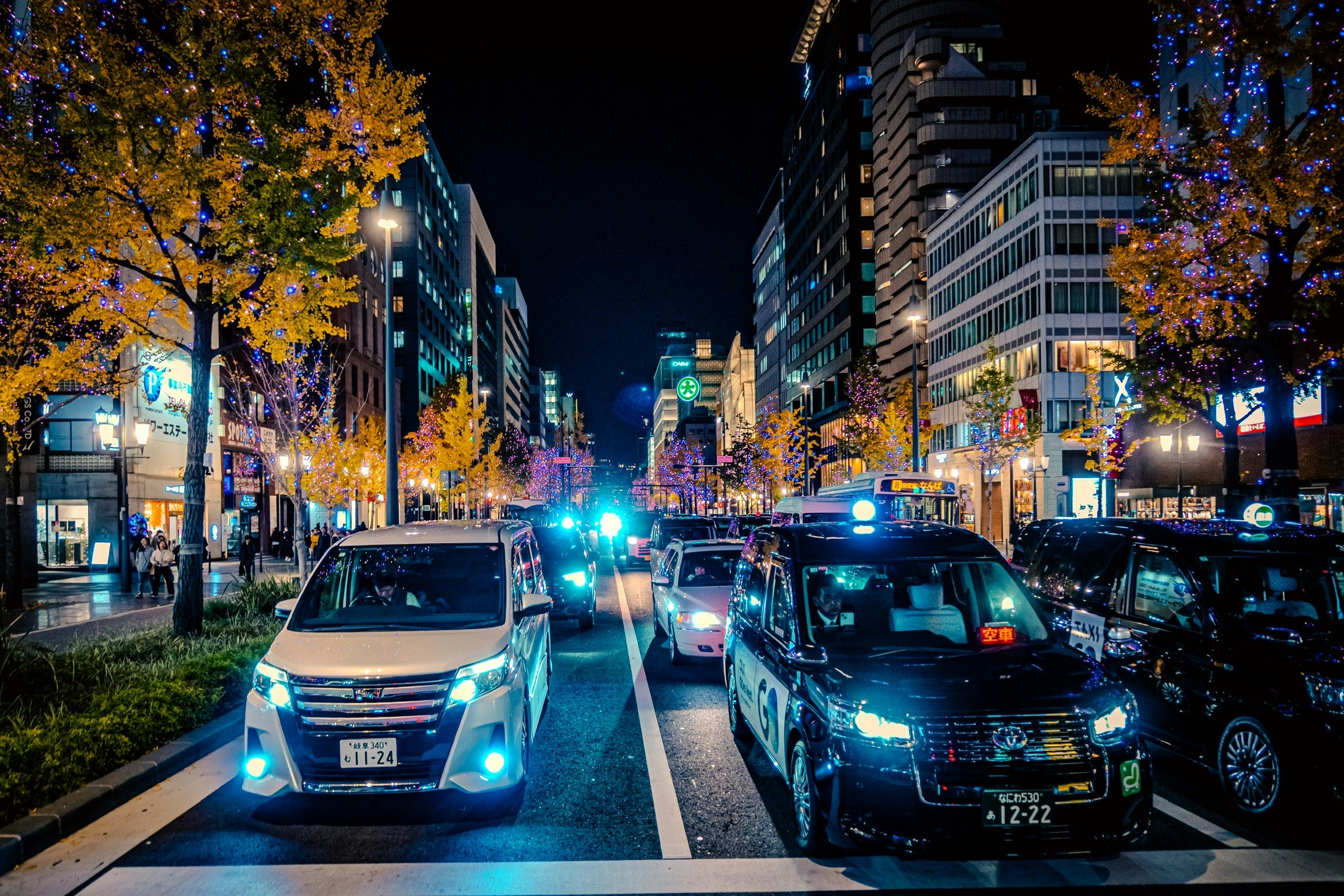 難波の夜の街路で並ぶ車とネオンの光
