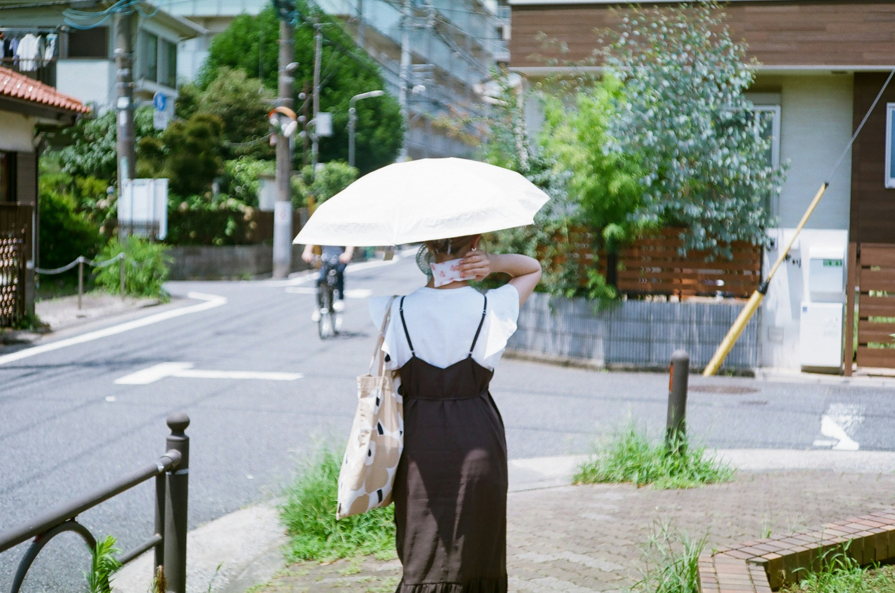 炎熱的日子裡，撐著傘的女性走在城市街道上