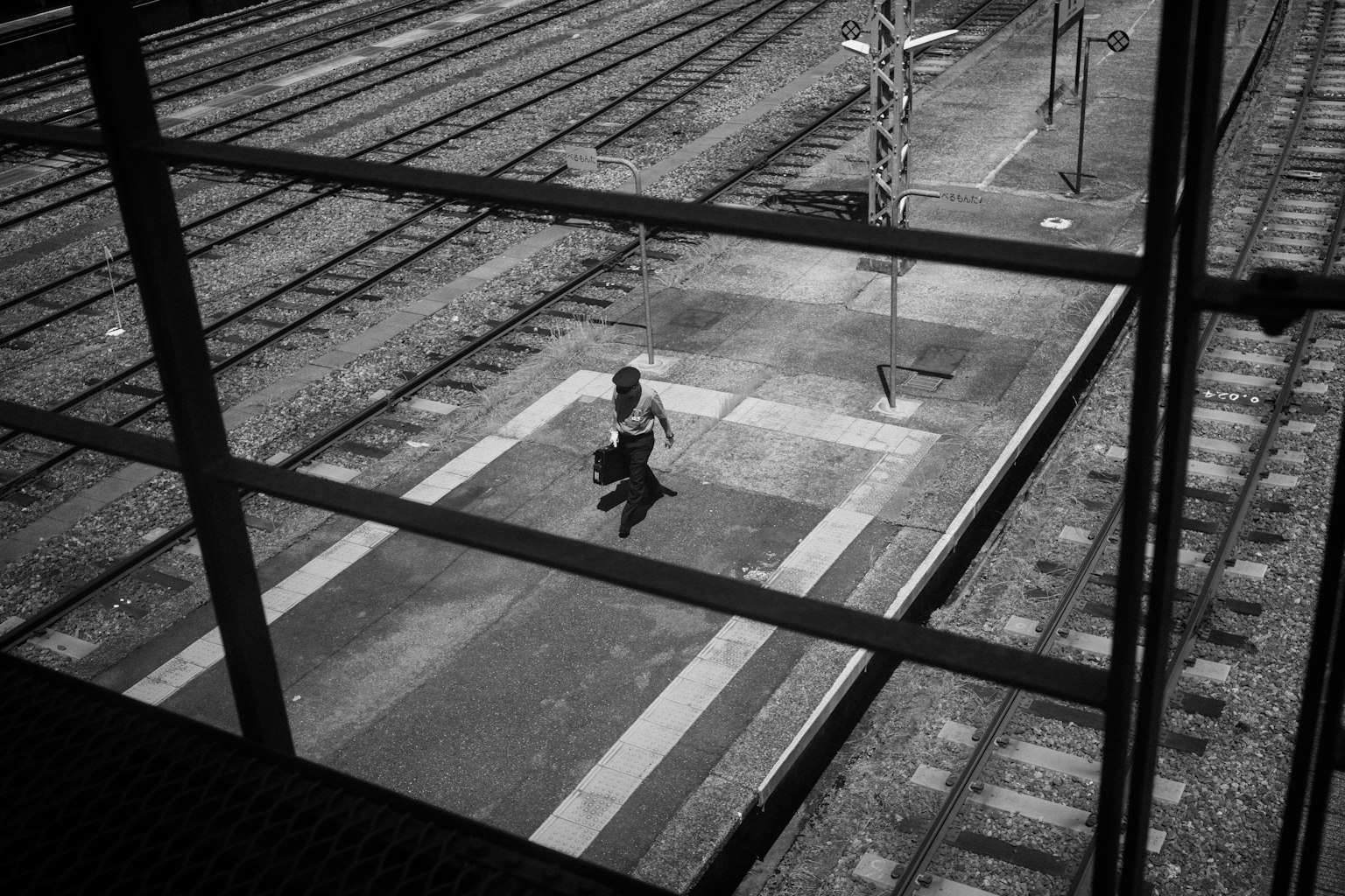 Eine Person, die auf einem Bahnsteig in einem Schwarz-Weiß-Bahnhof geht