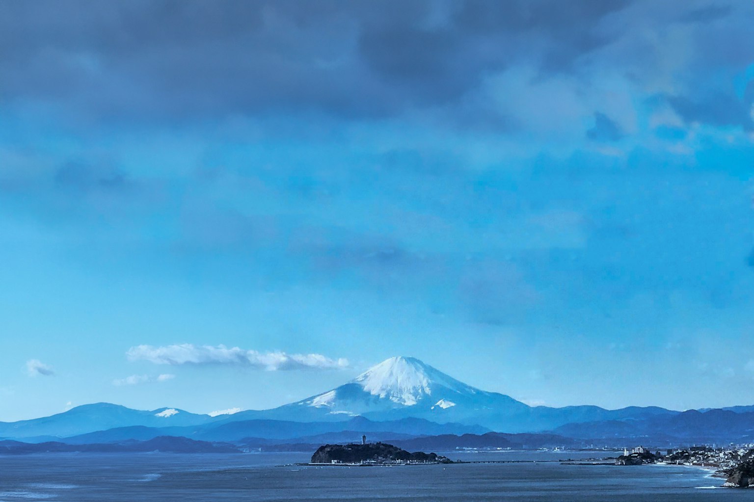 Vue pittoresque d'une montagne enneigée sous un ciel bleu au-dessus de l'océan