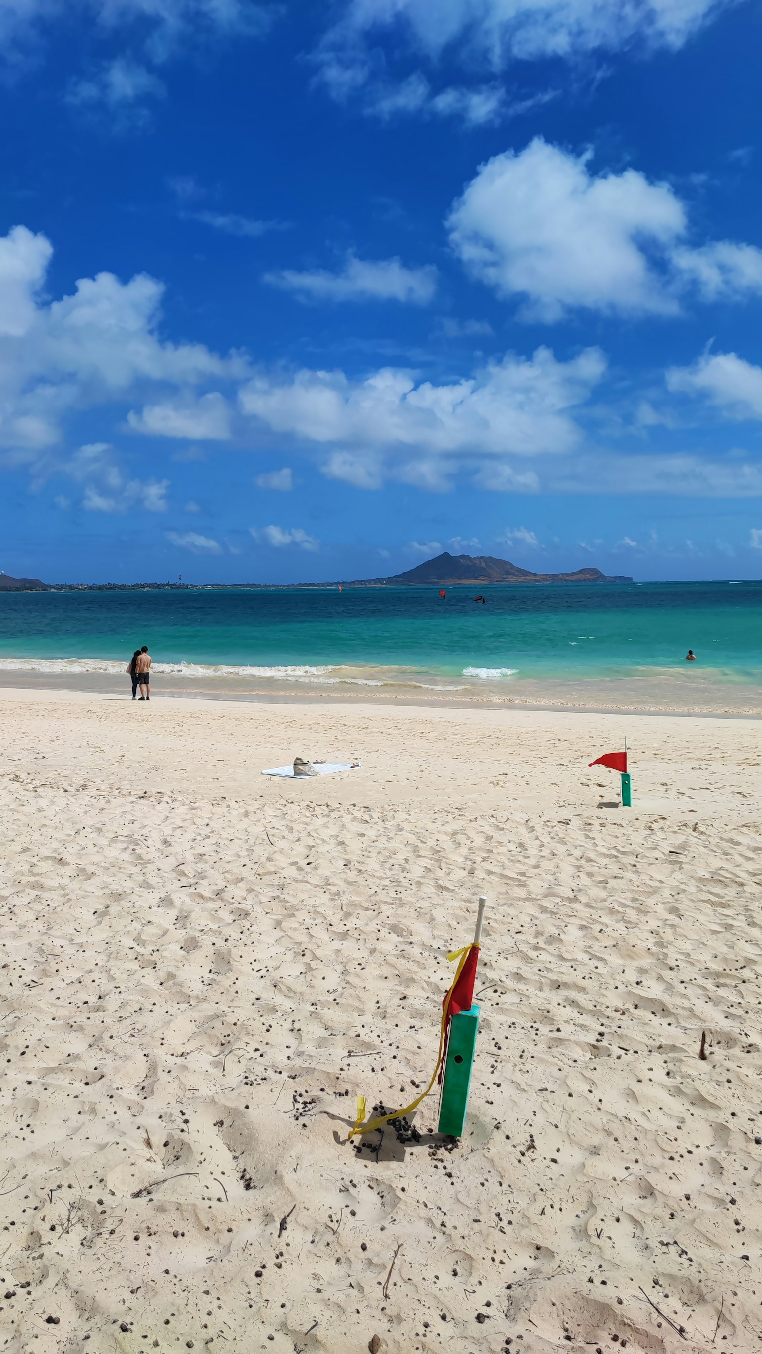 Pemandangan pantai dengan langit biru dan pasir putih dengan seseorang yang berjalan