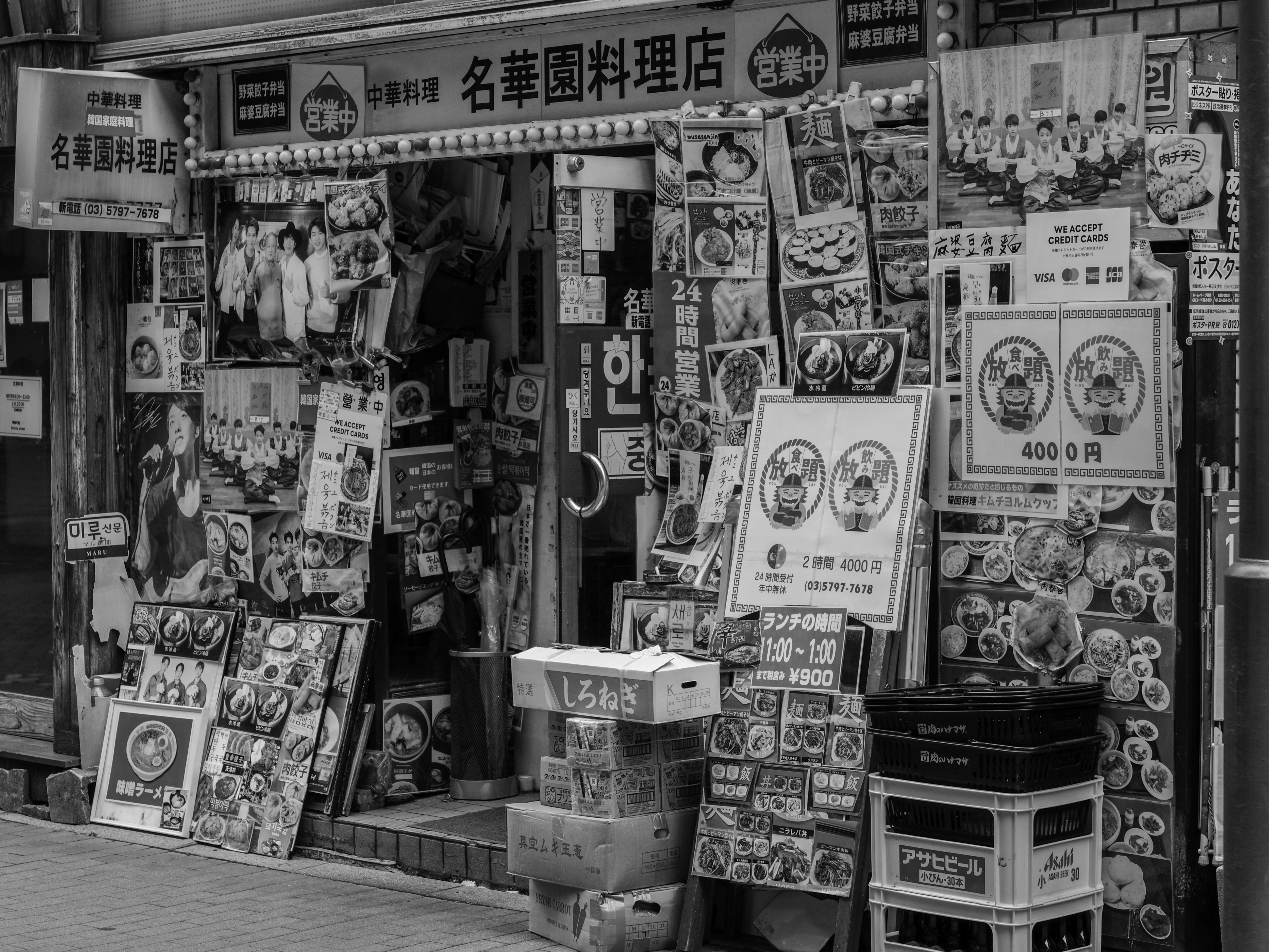 名韓国料理店の店先に並ぶメニューやポスターの看板